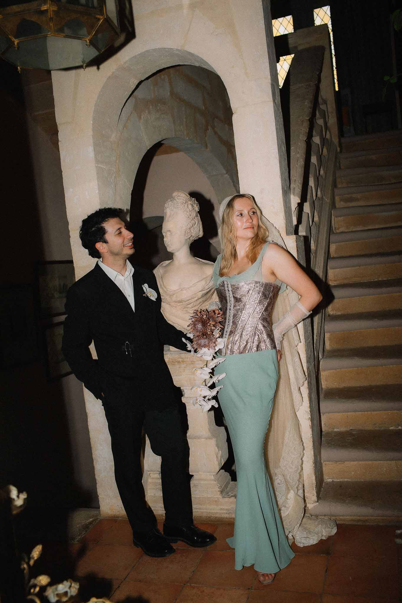 Couple posing inside Chateau St Victor Lacoste near decorative statue