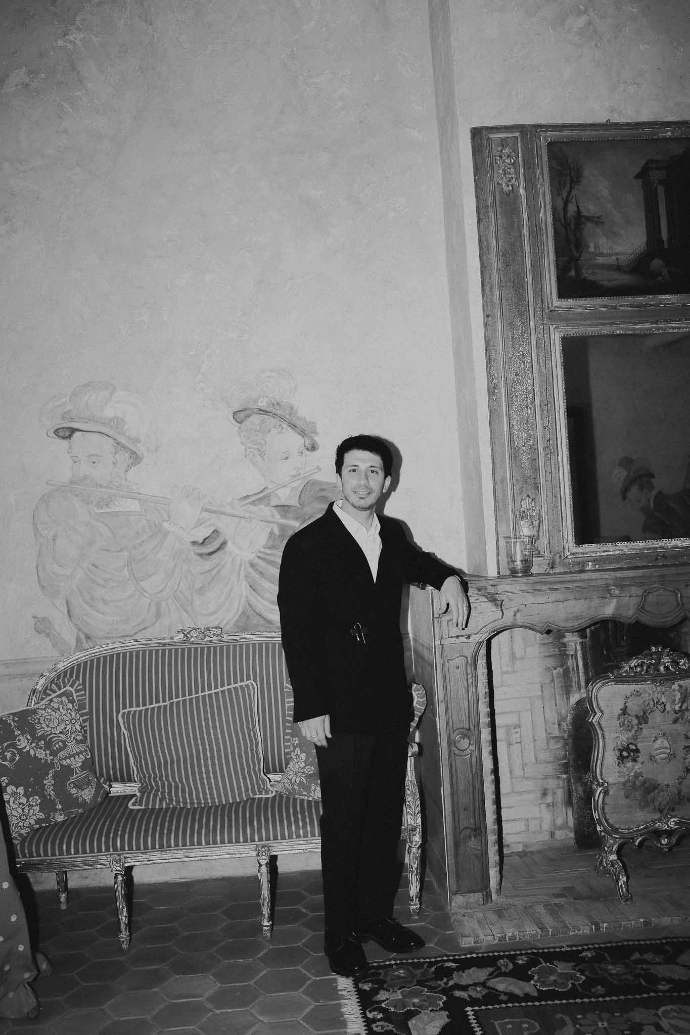 Groom getting ready beside vintage fireplace at Chateau St Victor Lacoste