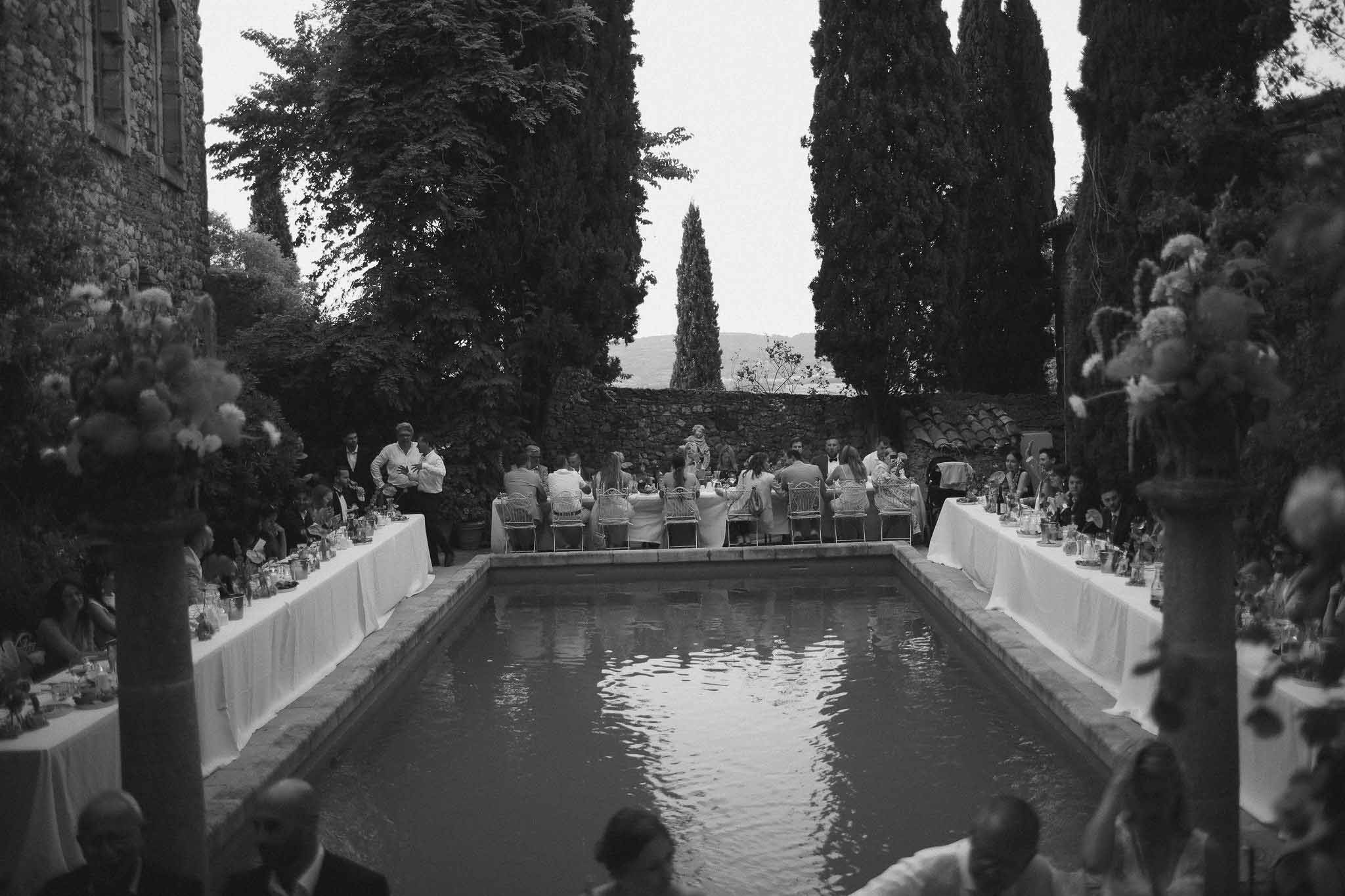 Guests seated at long reception table beside pool at Chateau St Victor Lacoste