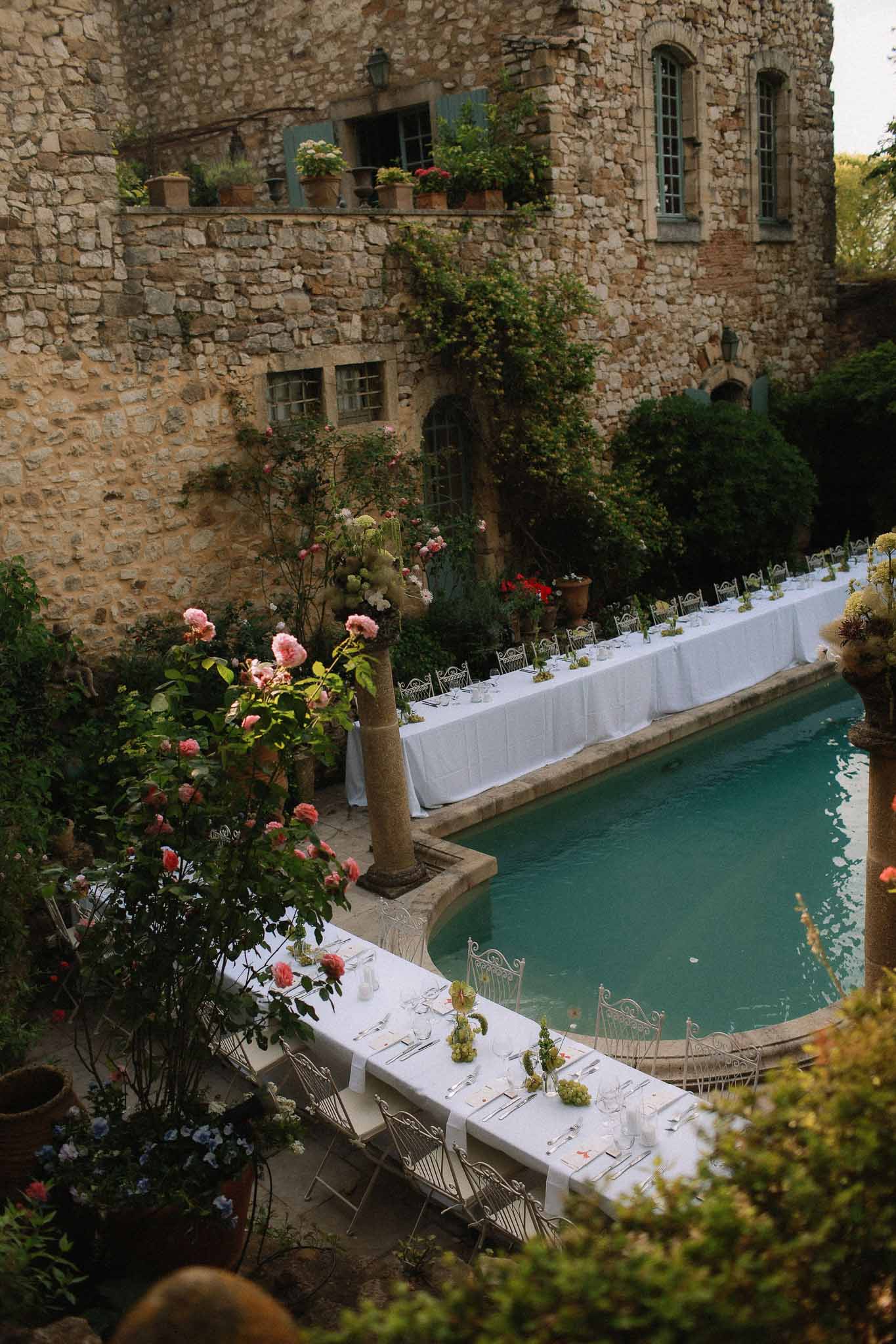 Long reception tables set up beside the pool at Chateau St Victor Lacoste