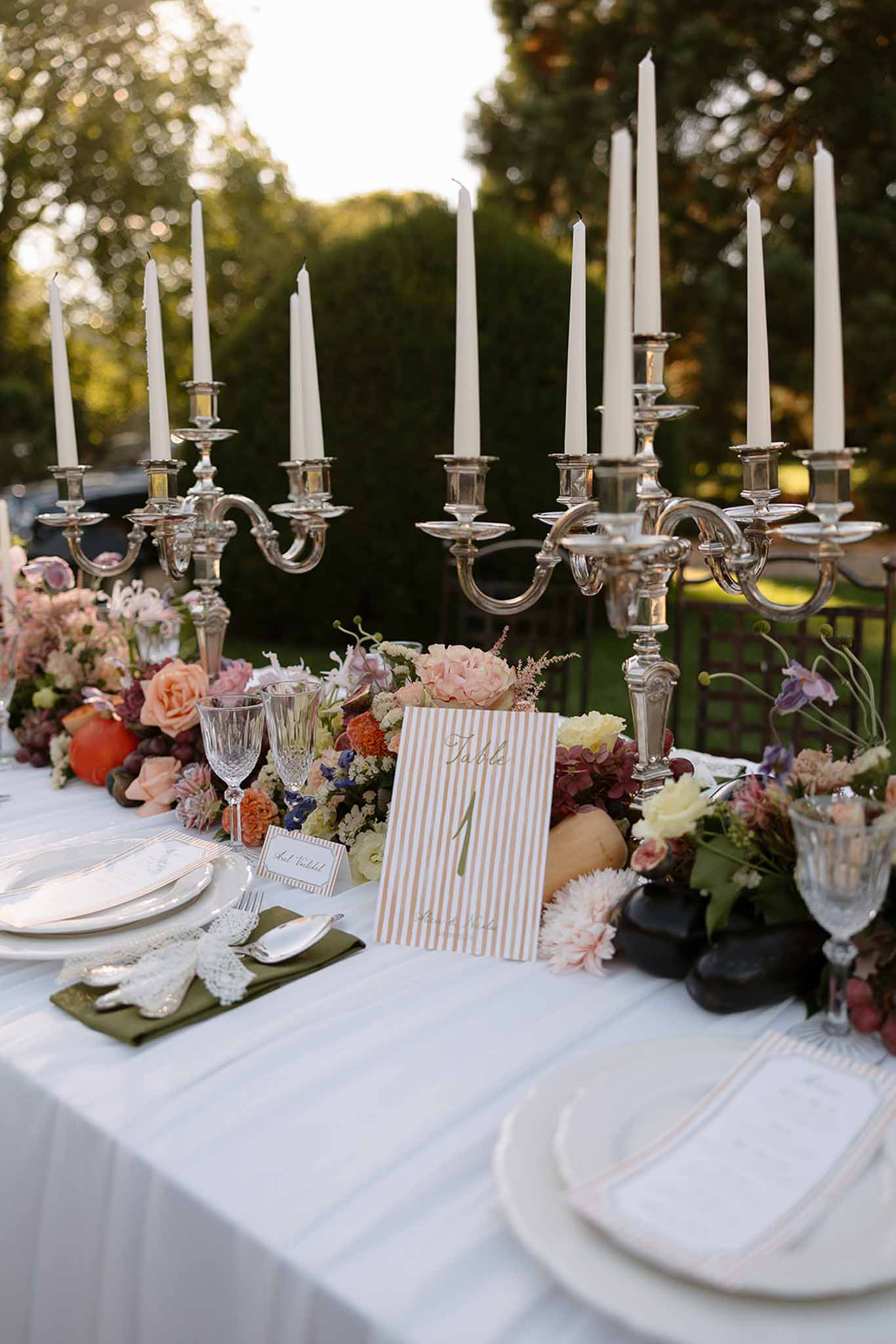 Autumn reception table with peach roses, burgundy dahlias, silver candelabras, crystal goblets, and olive green napkins