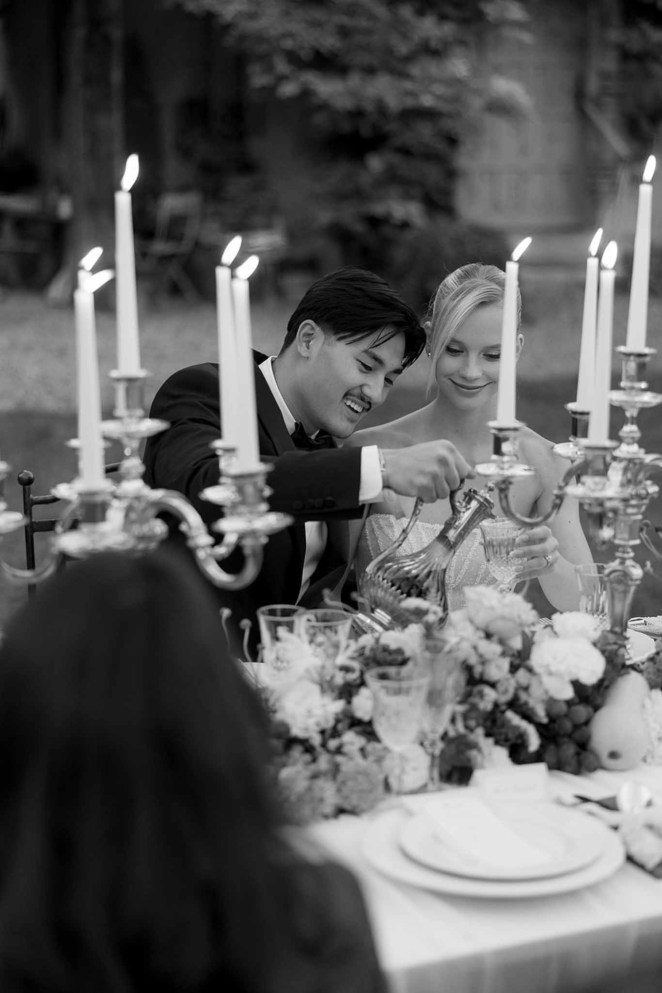Black and white photo of wedding reception table setting in a garden with white roses