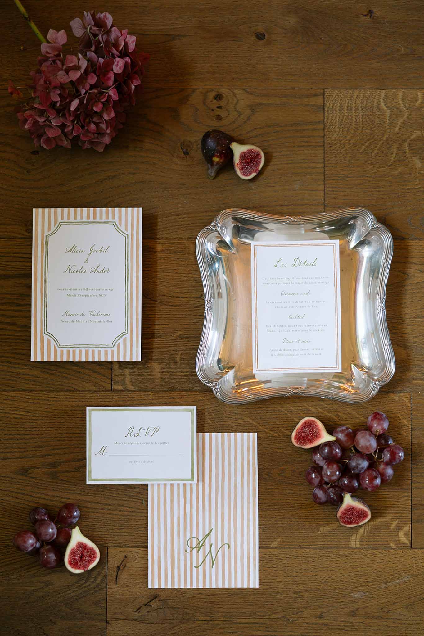 Terracotta-striped stationery suite with sage RSVP card, dried hydrangea, figs, and grapes on oak