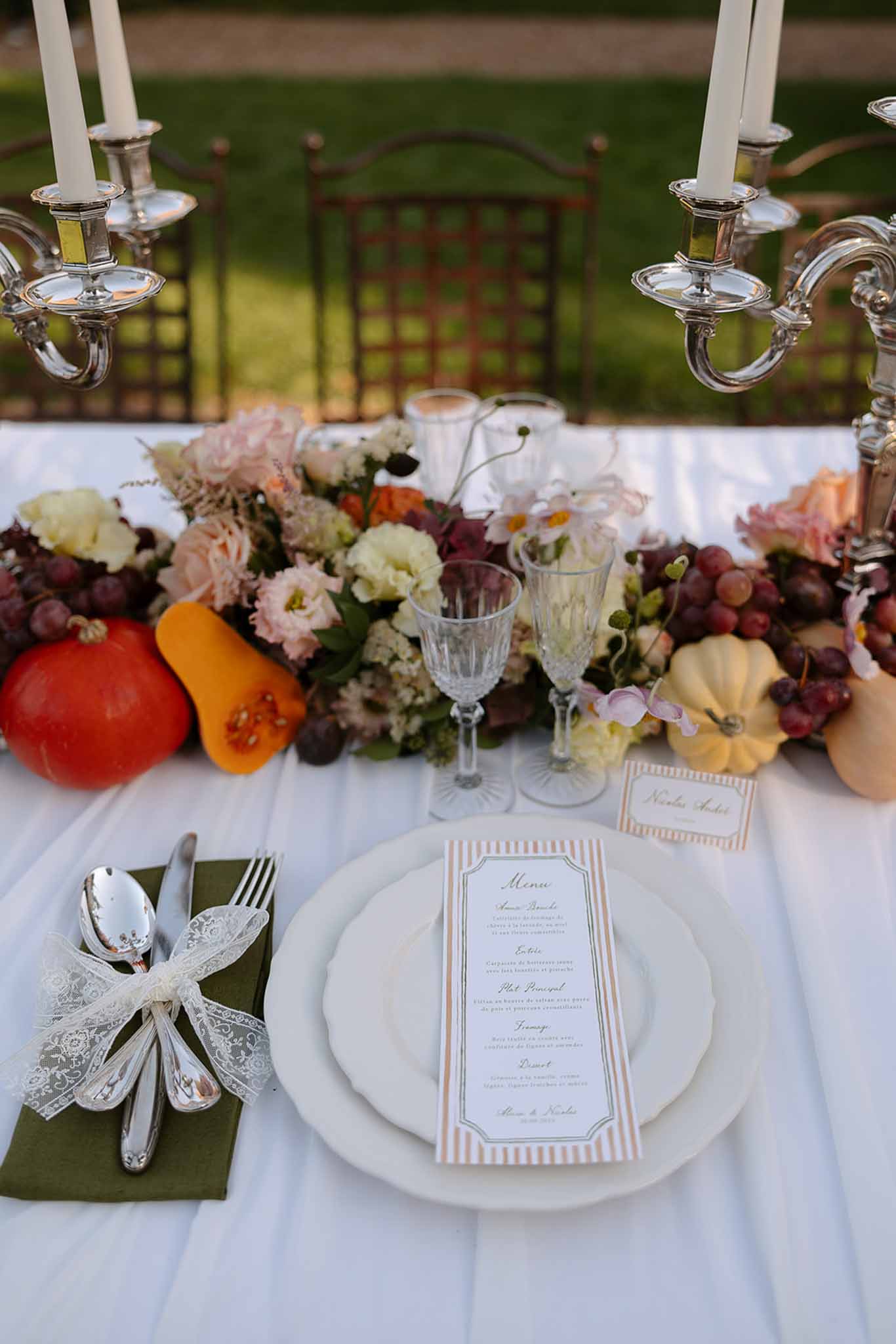 Autumn harvest table with pumpkins dark grapes blush roses peach striped menu and silver candelabras