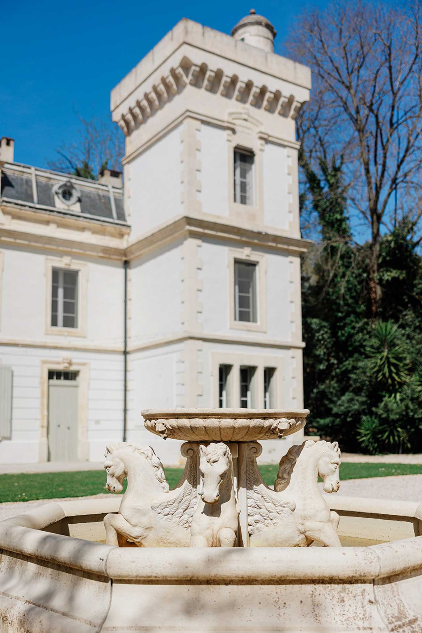 Classical French chateau exterior with Pegasus stone fountain in the foreground on manicured grounds