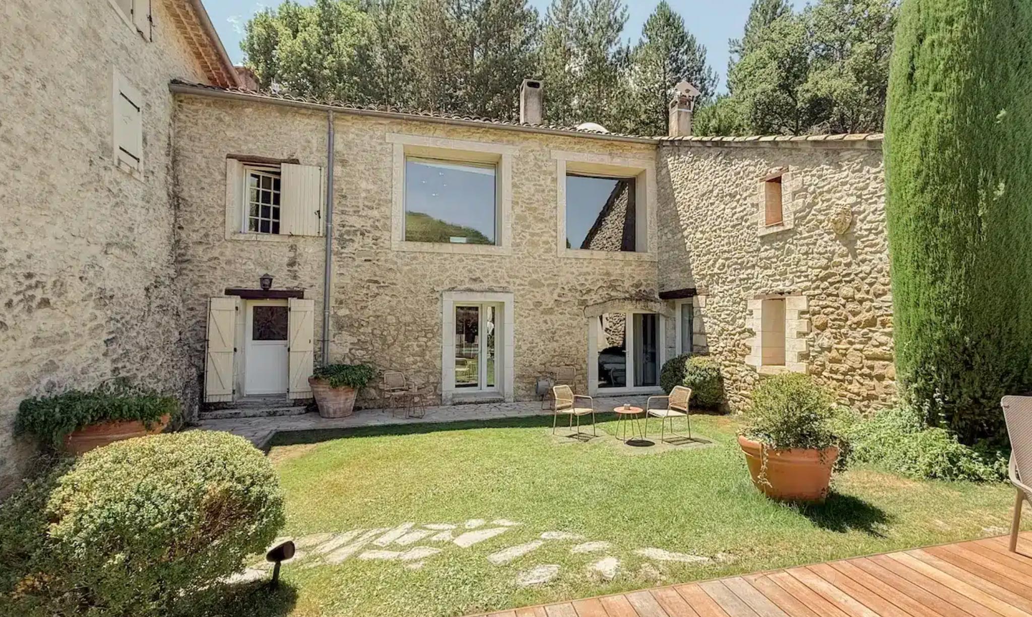 Stone farmhouse courtyard with white shutters terracotta roof and box hedge garden seating area