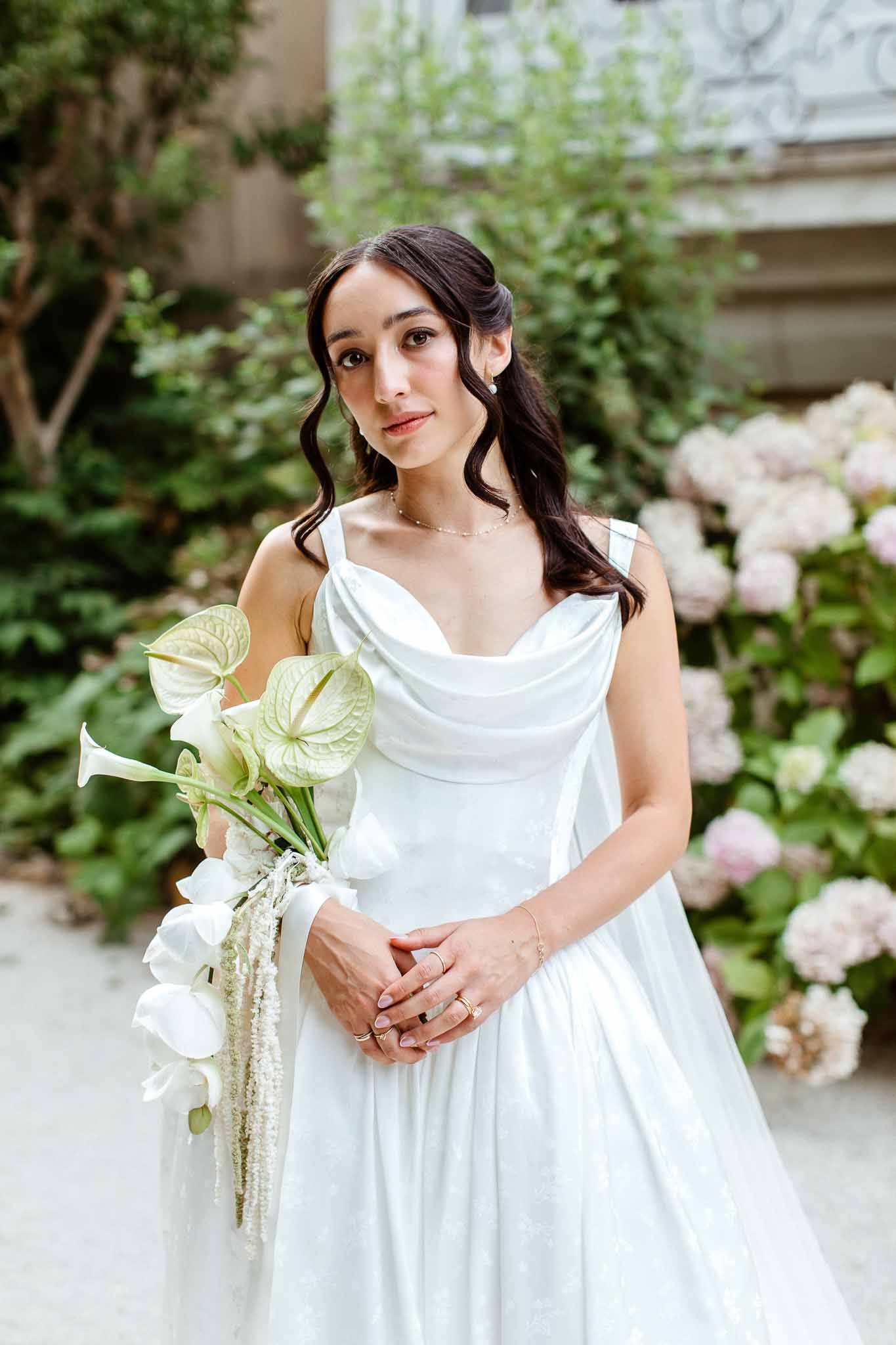 Bride in white cowl-neck satin gown with anthurium calla lily and orchid bouquet and gold jewellery