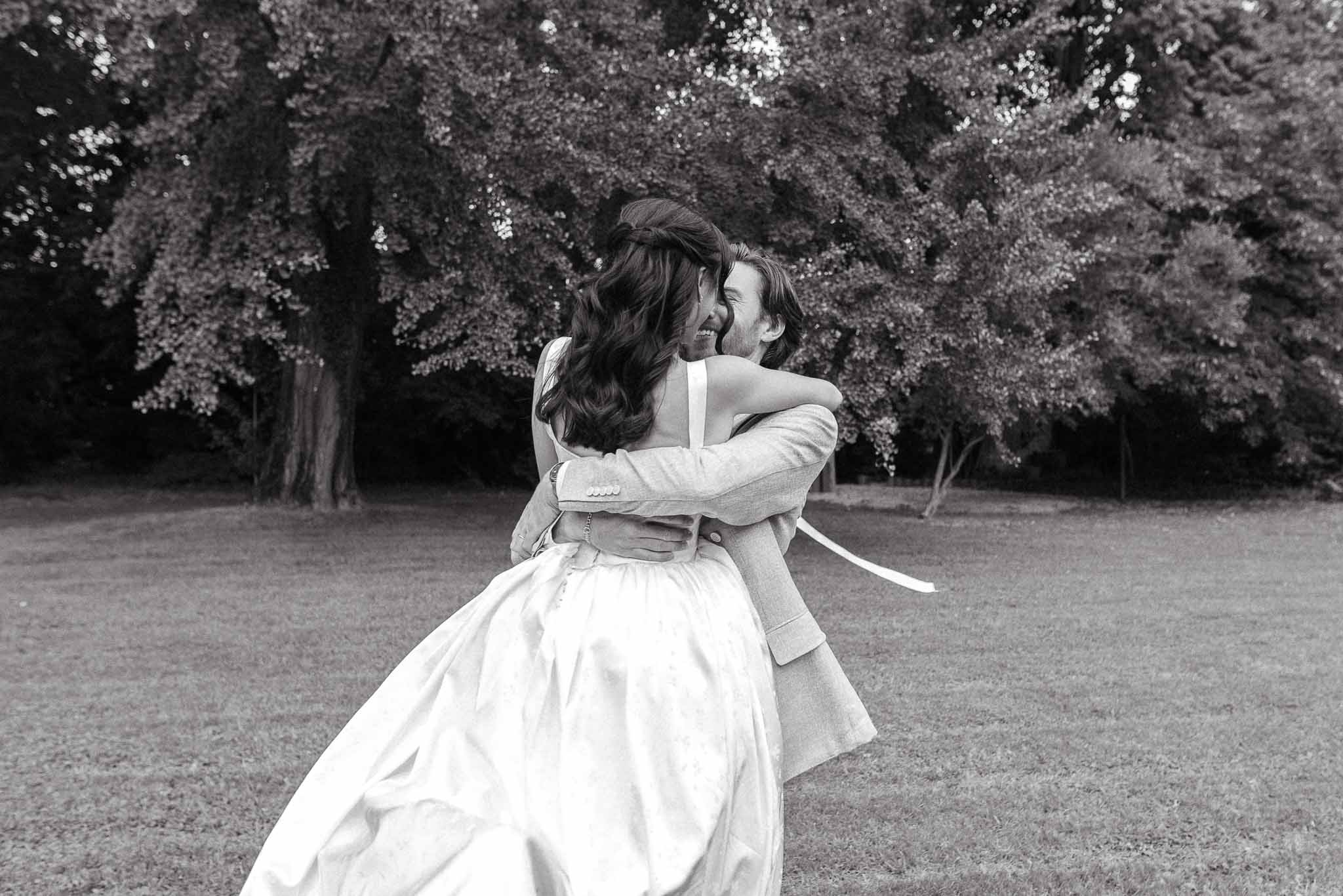 Black and white couple spinning and laughing on open lawn with dress skirt swinging outward