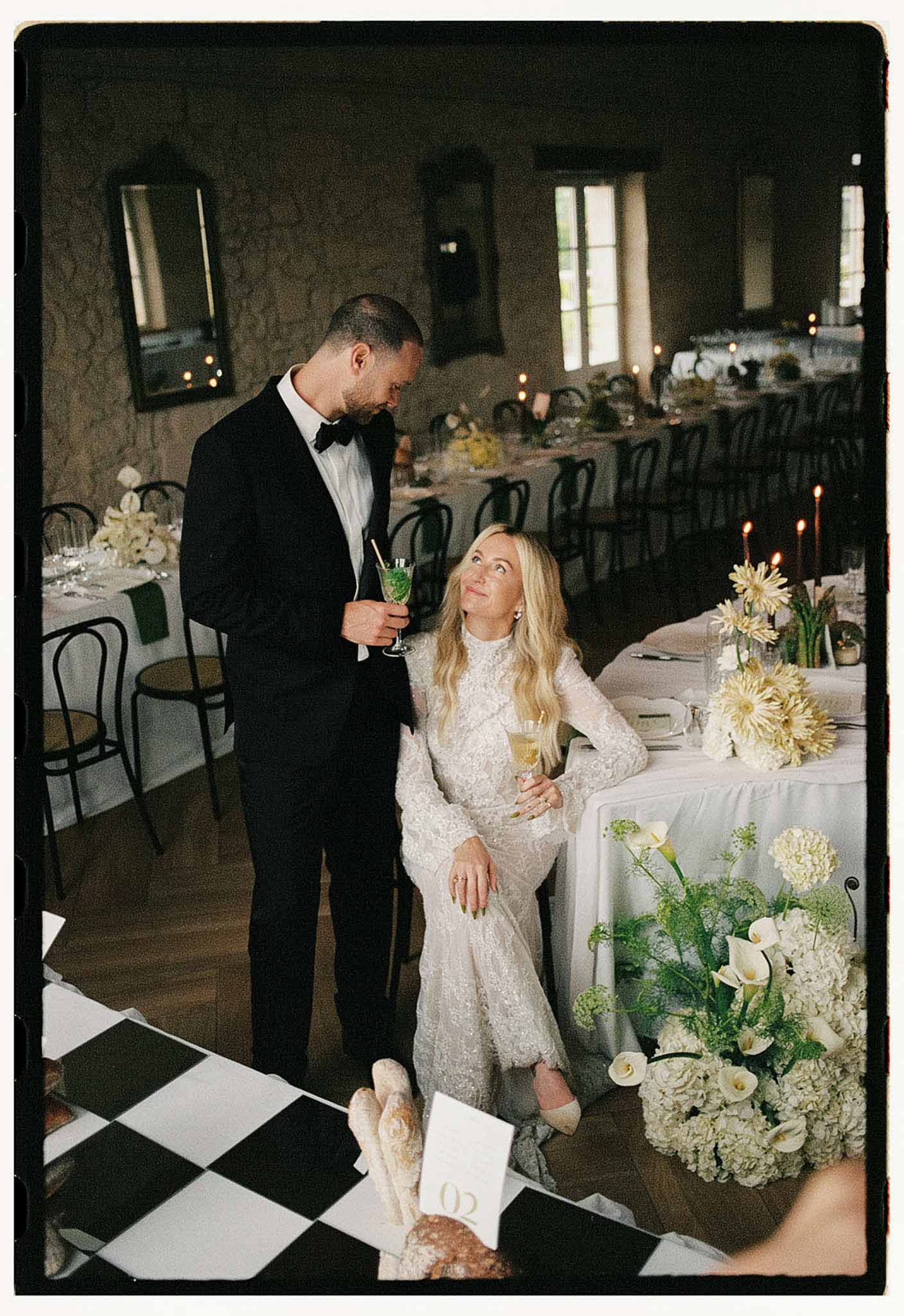 Couple shares quiet moment at reception table with white hydrangea and yellow gerbera centerpieces