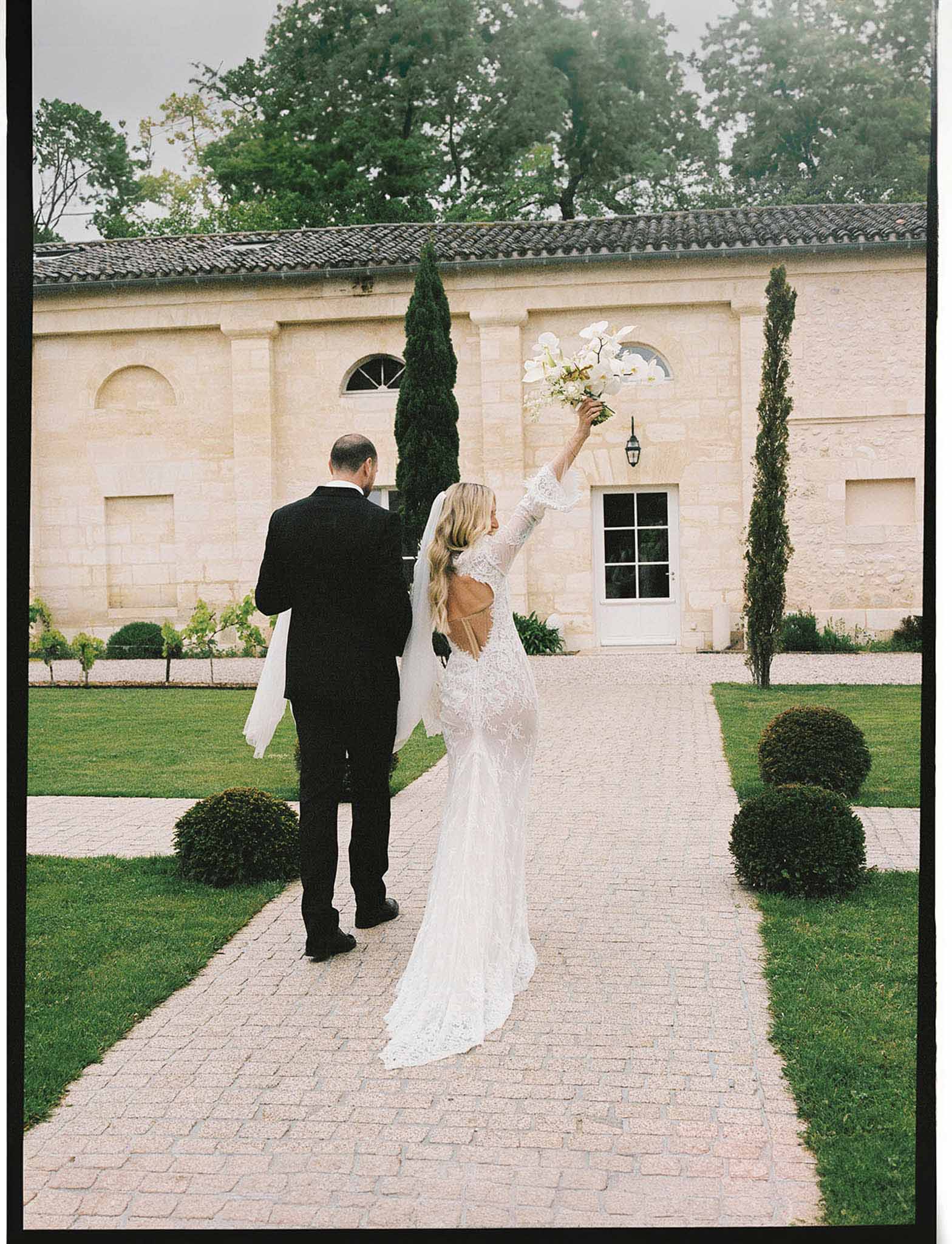 Bride and groom walking hand in hand in a garden