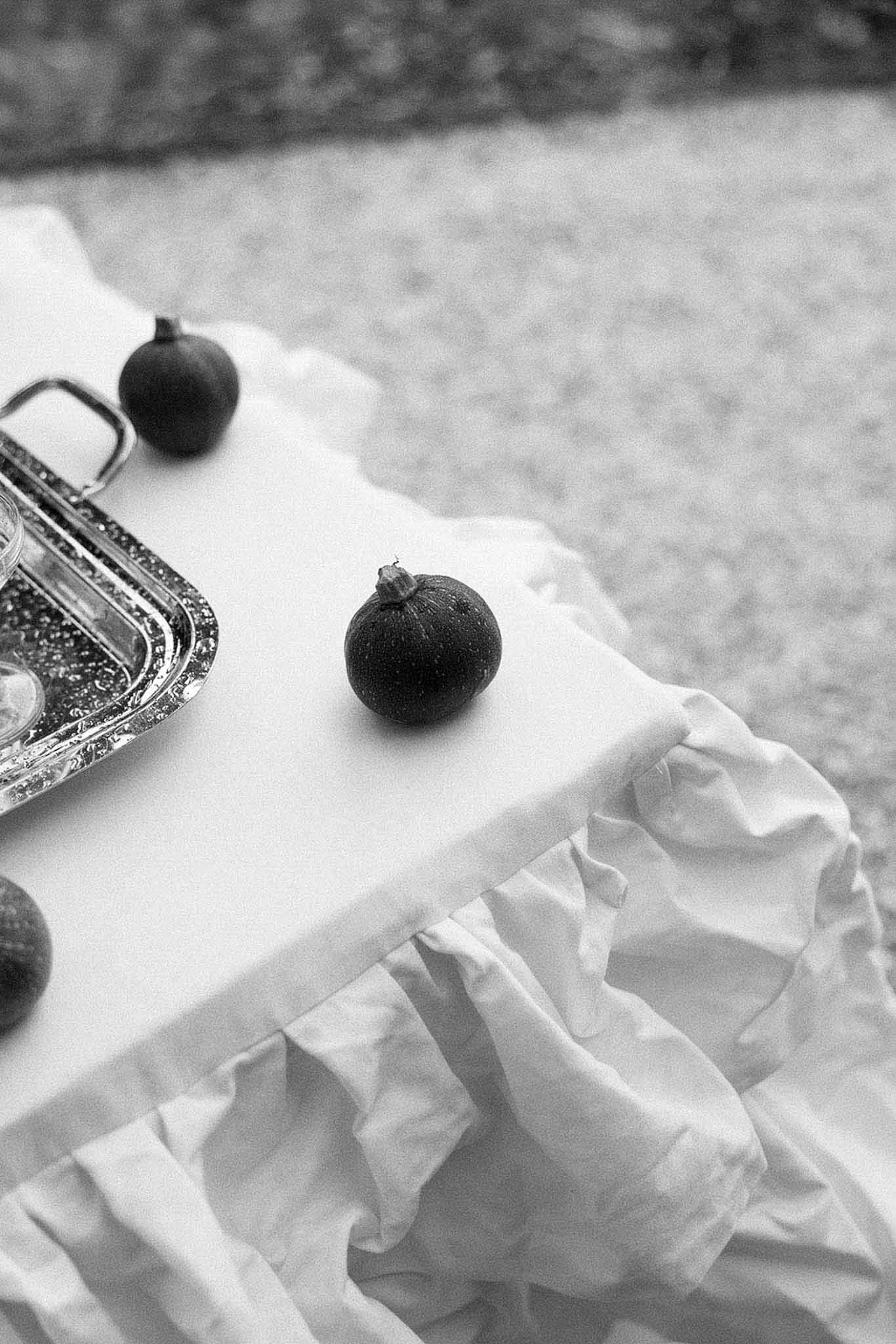 Black and white close-up of figs on ruffled white linen with silver serving tray