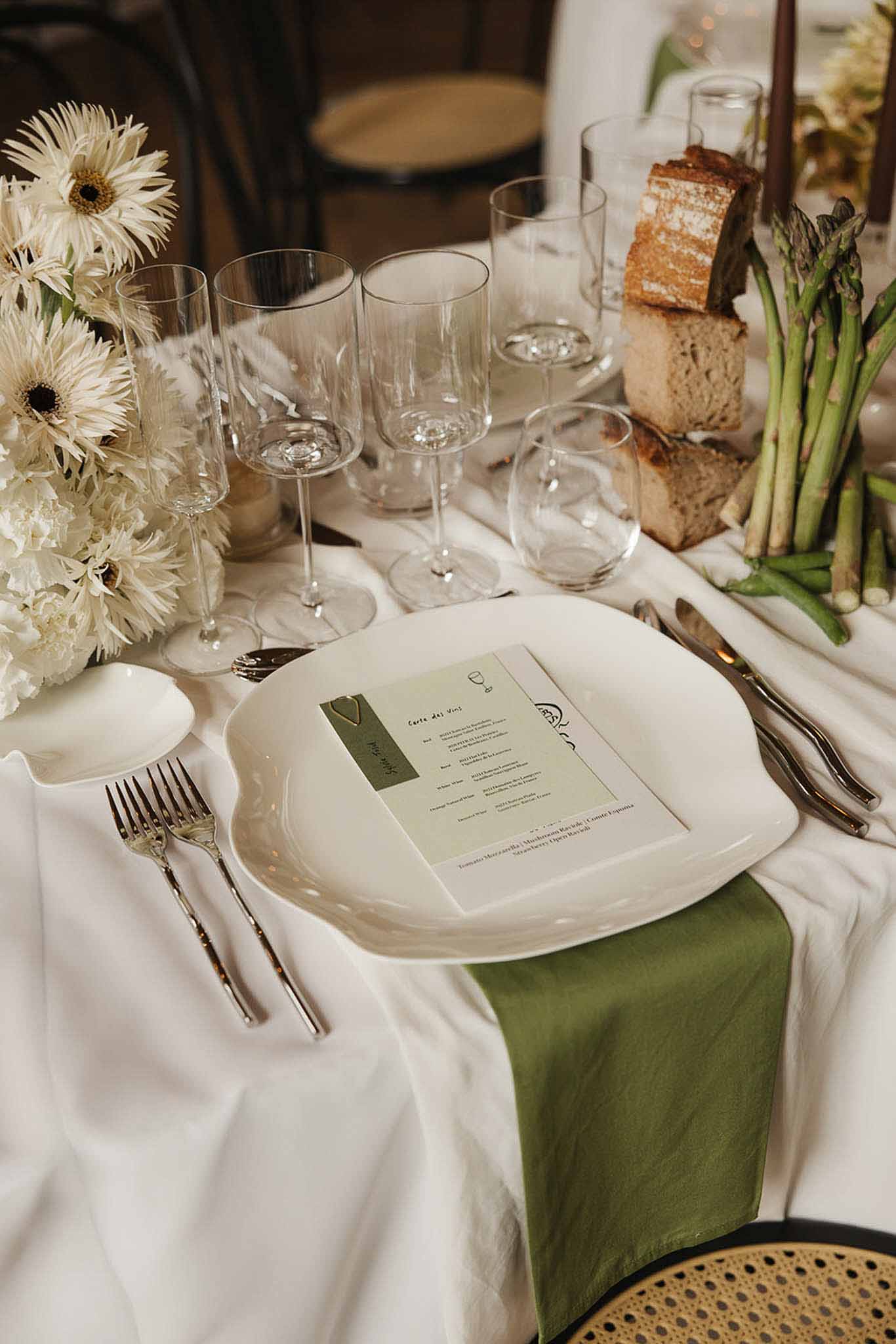 White gerbera and peony centerpiece with olive napkin, rustic bread, and asparagus on organic-edge plate