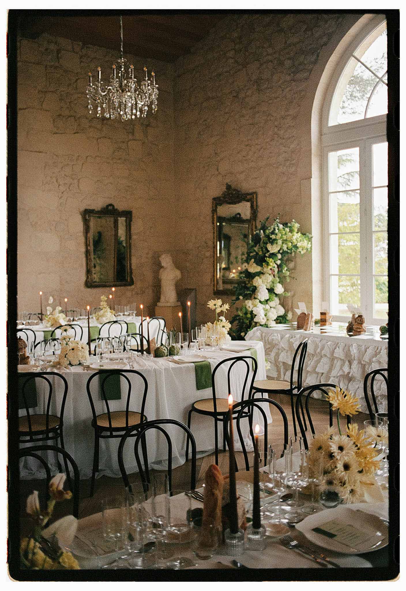Chateau ballroom reception with green napkins, black candles, yellow gerbera daisies, and crystal chandelier