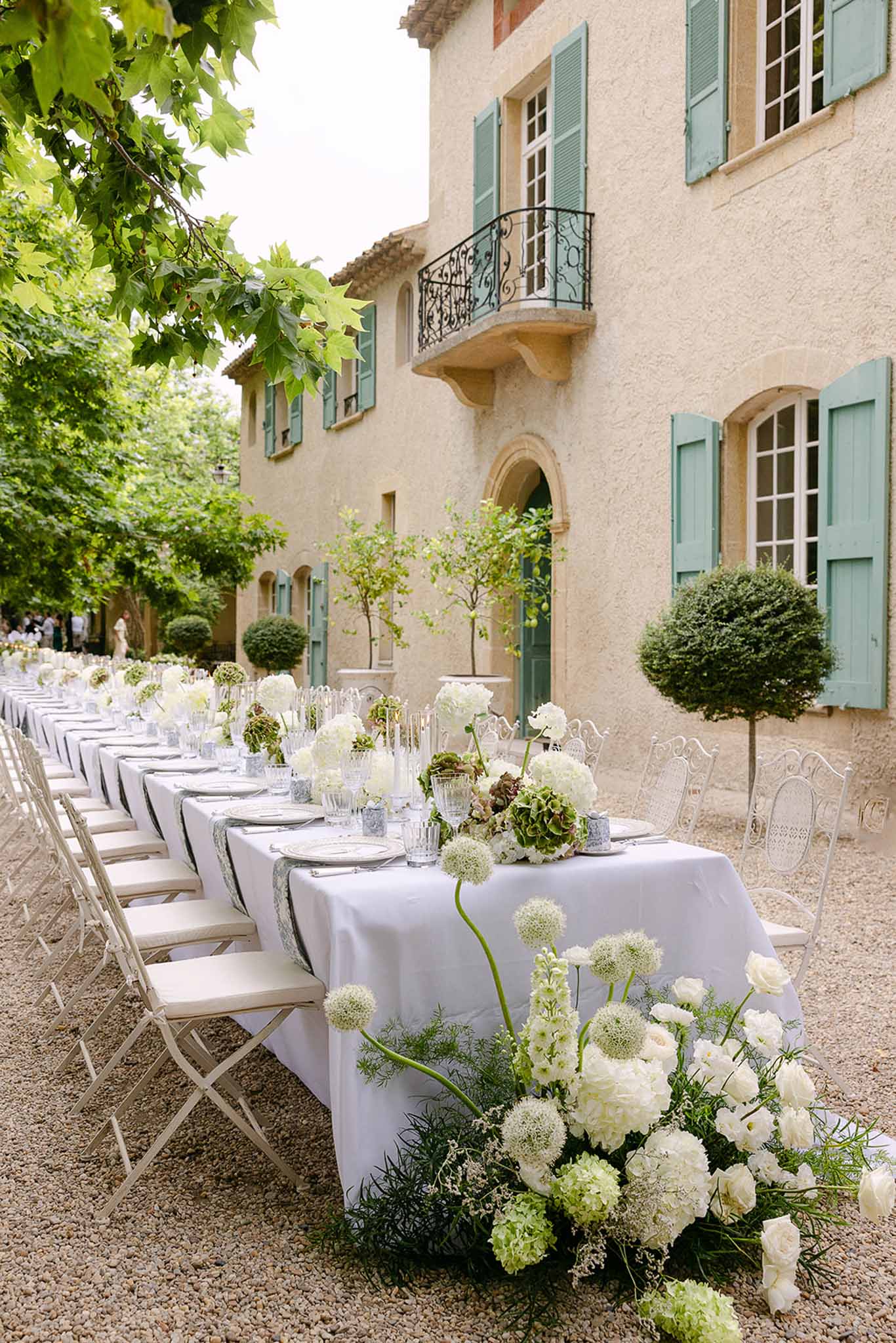 Long table with white allium and hydrangea runner, bistro chairs, at Provencal mas with sage shutters