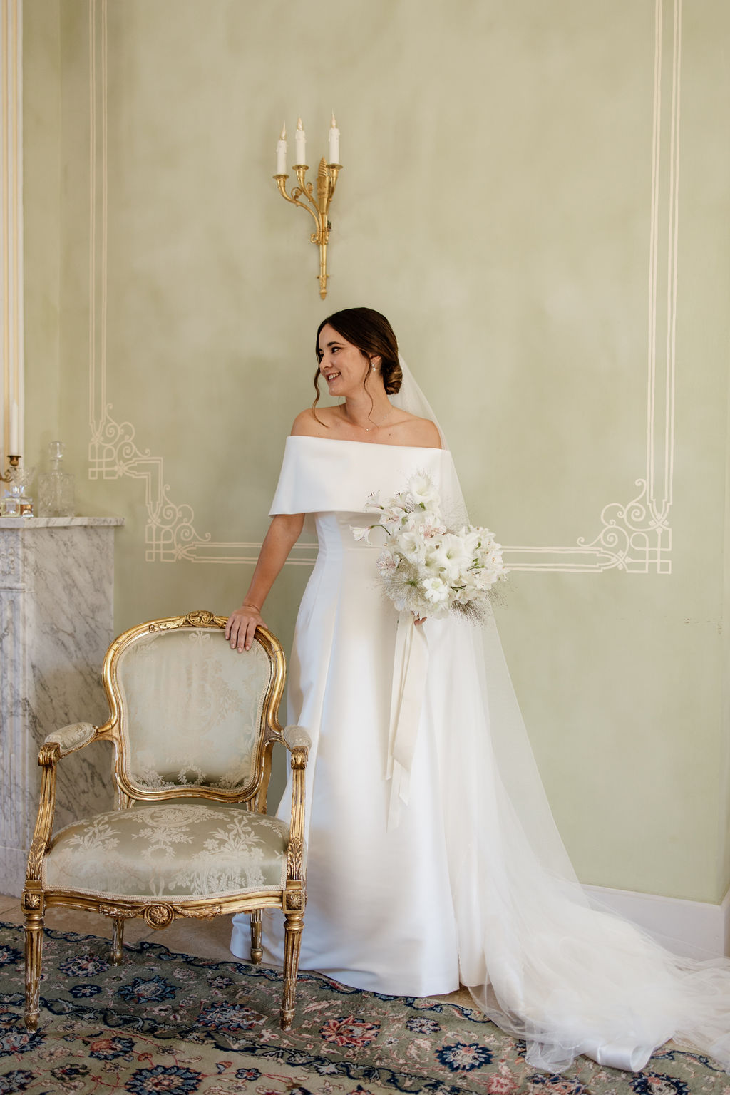Bride in ivory satin gown with cathedral veil holding anemone and sweet pea bouquet in sage-panelled room