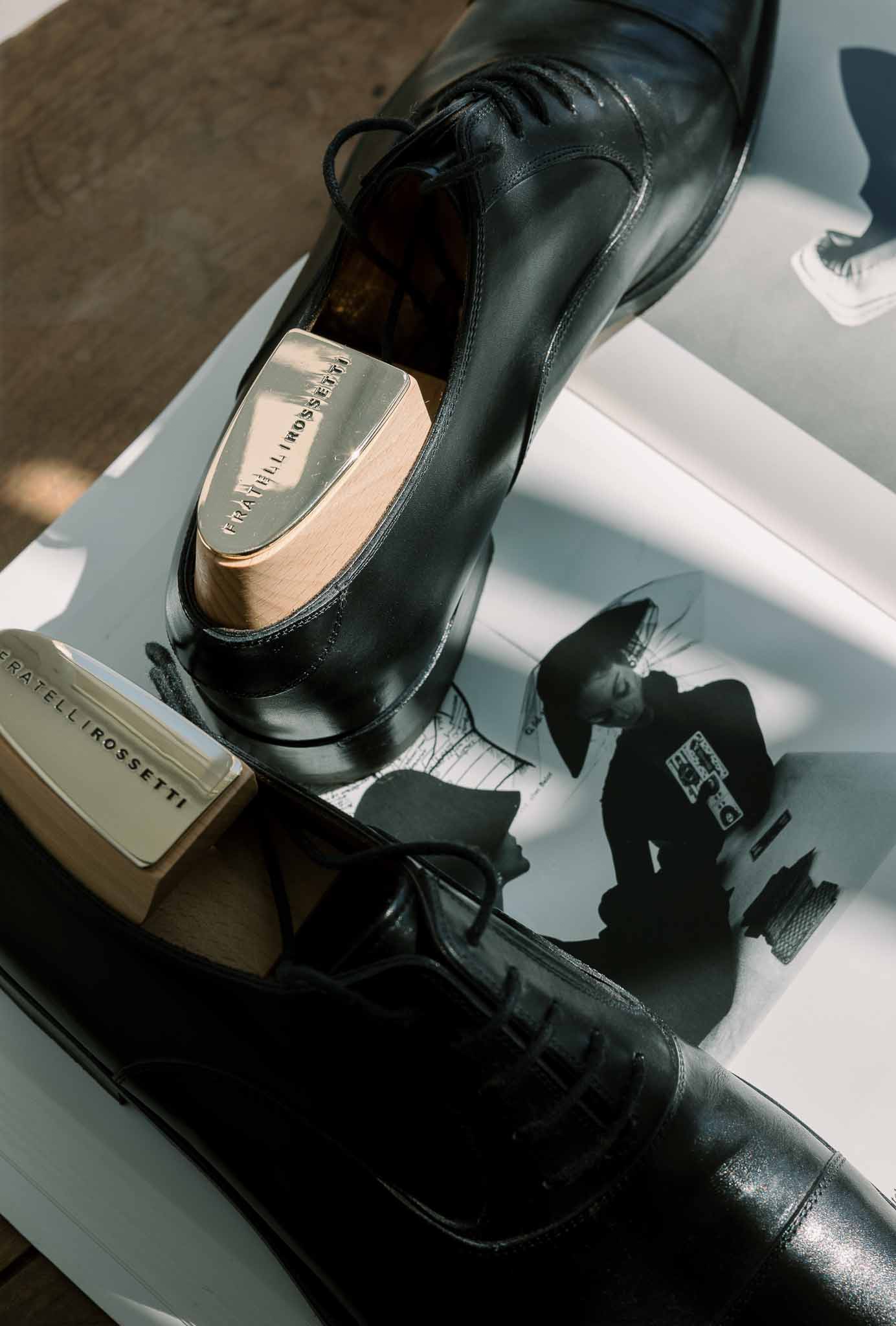 Fratelli Rossetti black leather Oxford shoes with branded wooden shoe trees on printed page