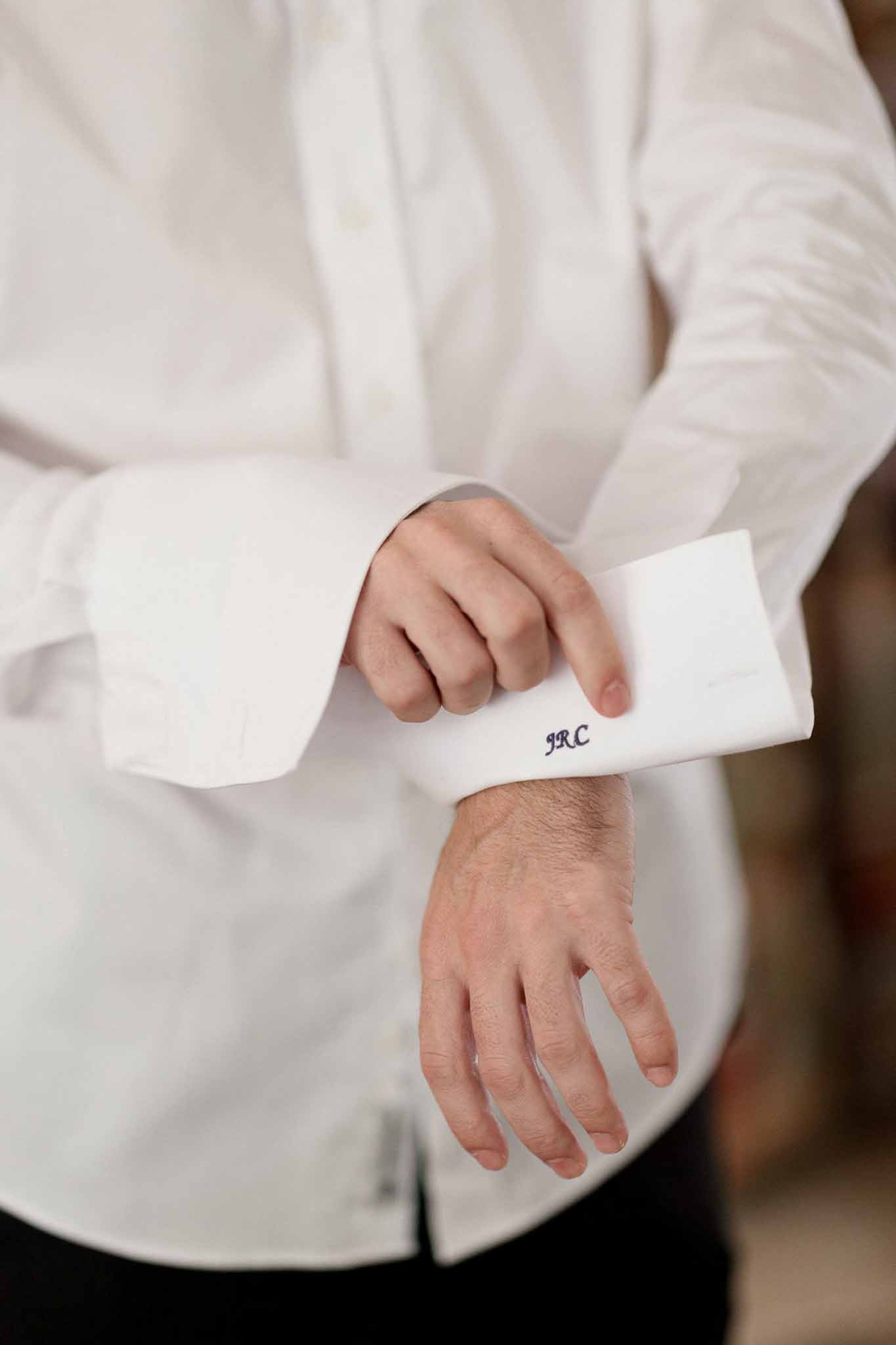 Close-up of groom's monogrammed JRC navy embroidered cuff on white dress shirt