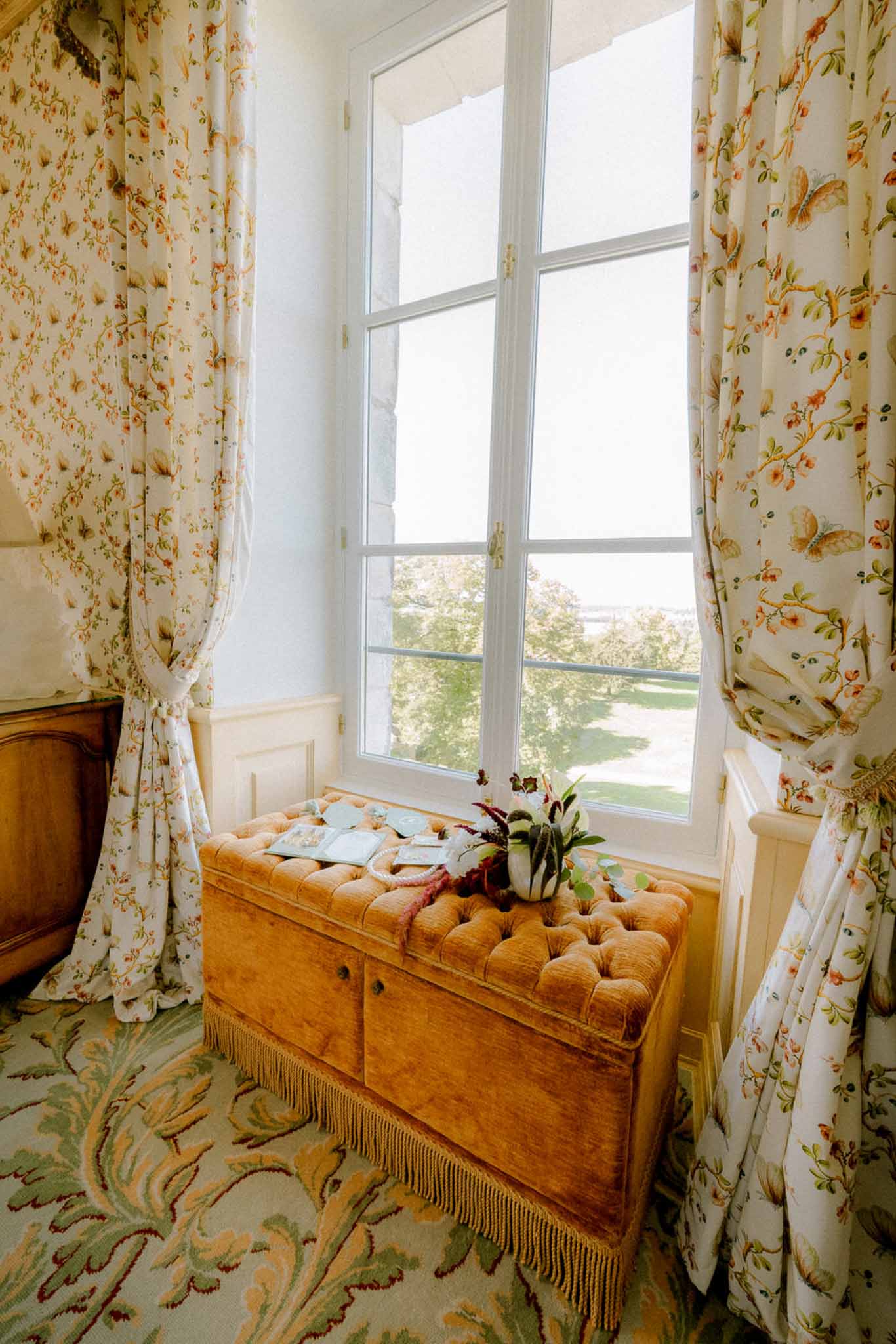 Gold velvet ottoman with wedding stationery and burgundy floral arrangement in chateau bridal suite