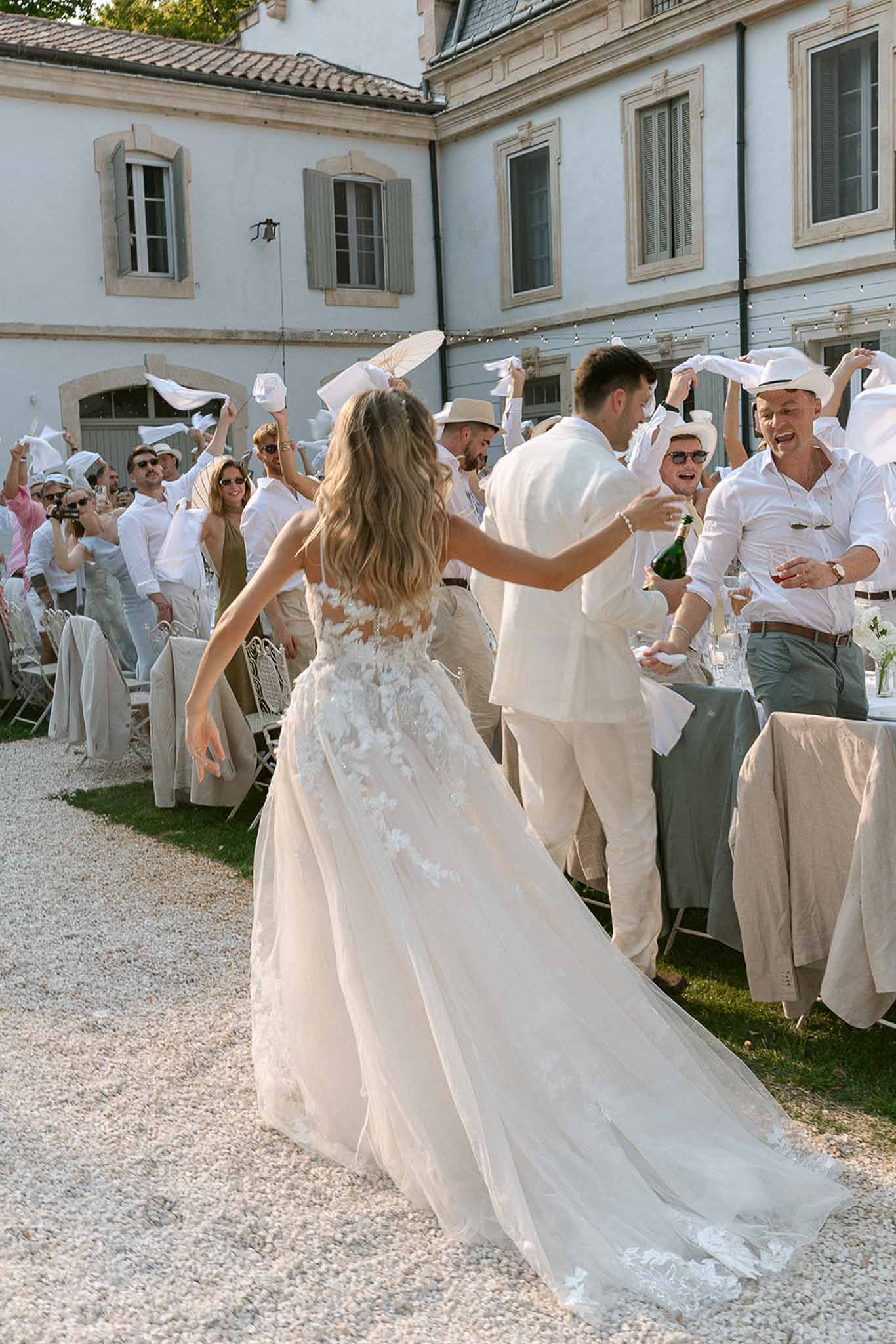 Bride and groom enter outdoor reception as 40 guests wave white napkins in French entree tradition