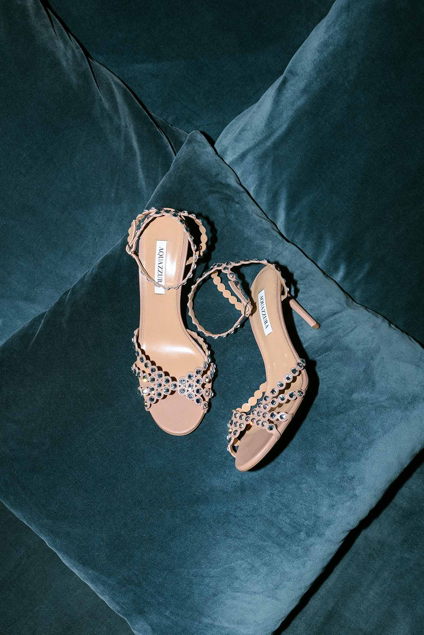 Aquazzura bridal heeled sandals with crystal embellishments on a teal velvet surface