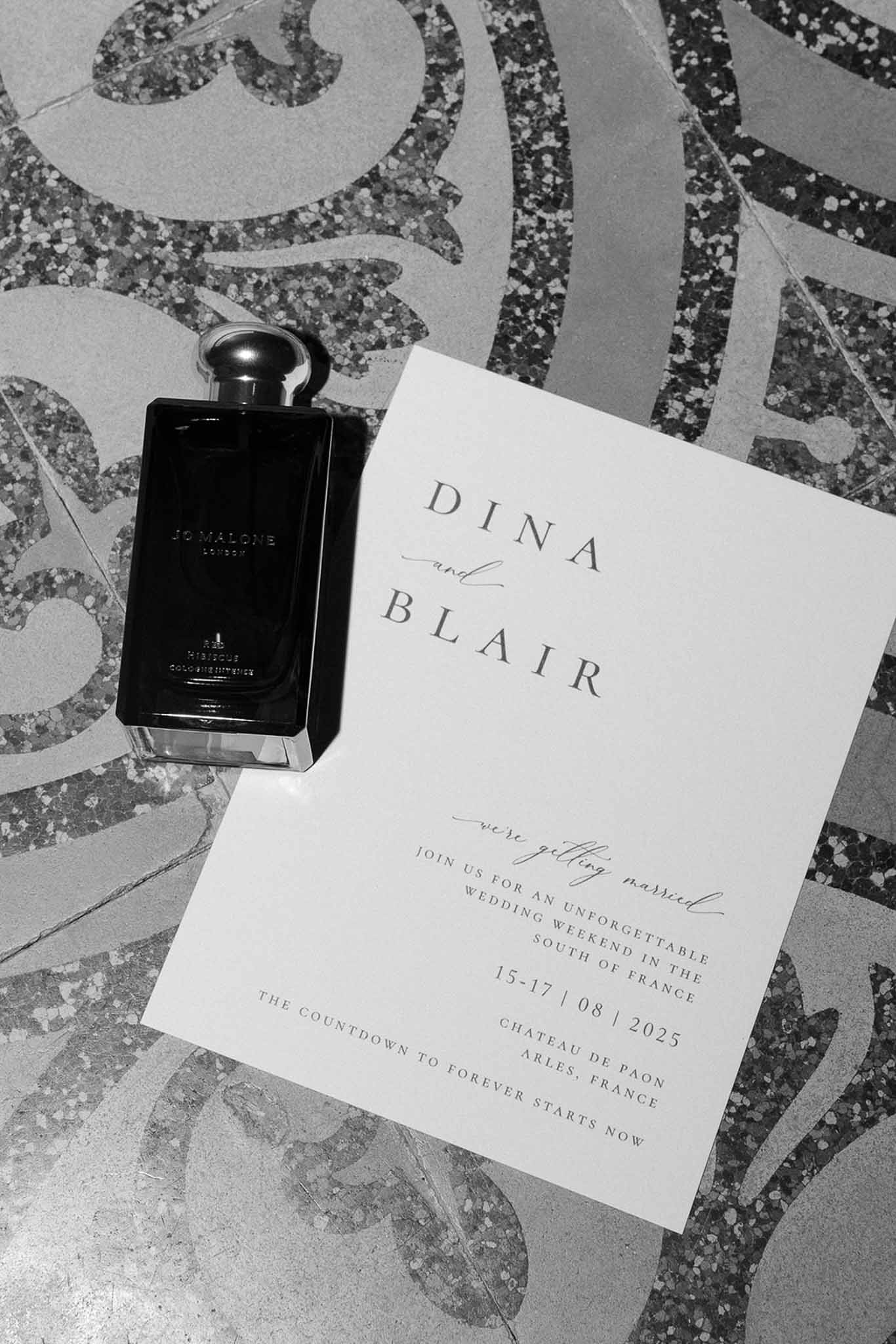 Black and white flat lay of modern invitation for Chateau de Paon with Jo Malone perfume on terrazzo