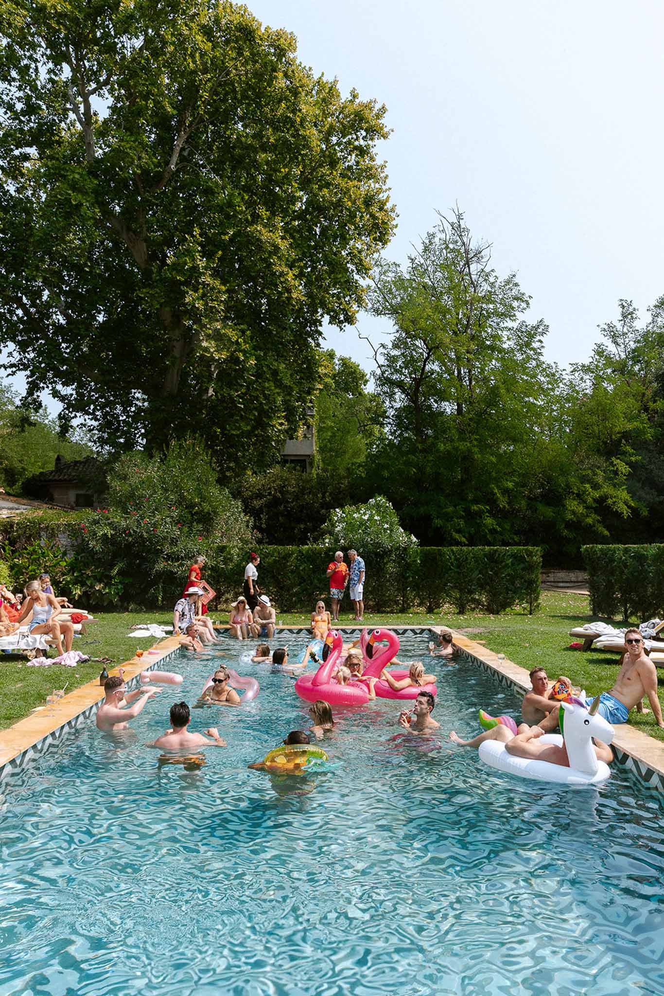 Pool party with flamingo and unicorn floats and 25 guests at French estate chevron-tiled pool