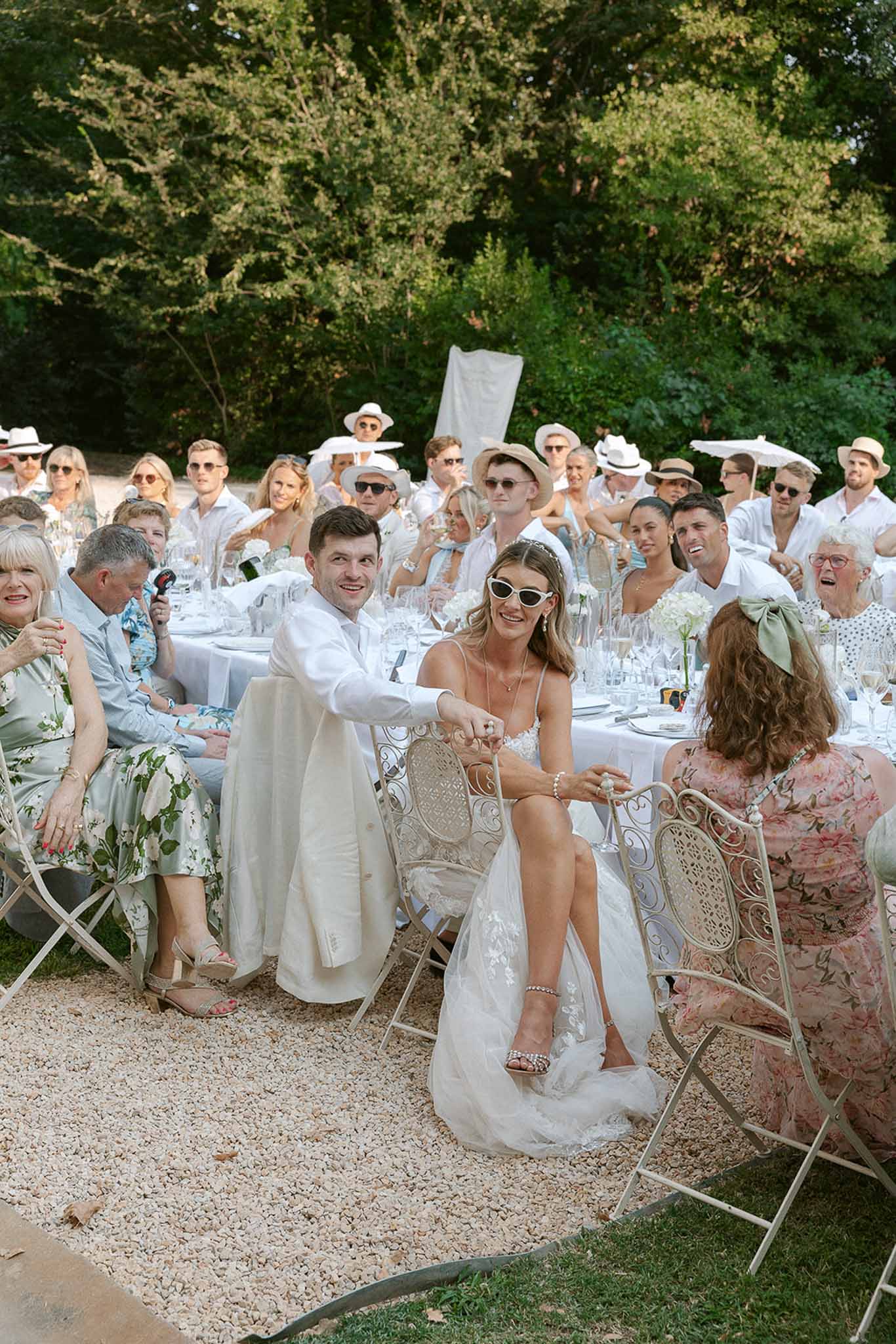 All-white dress code reception with 40 guests, white hydrangea centerpieces and wrought-iron chairs on gravel