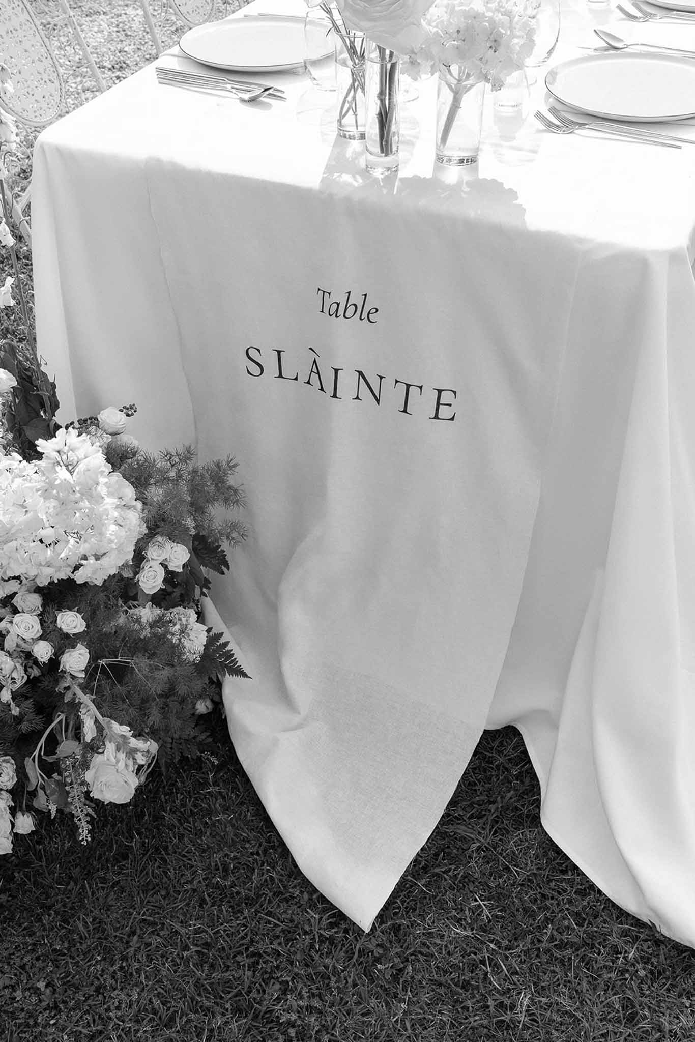 Black and white photo of wedding reception table setting with white roses