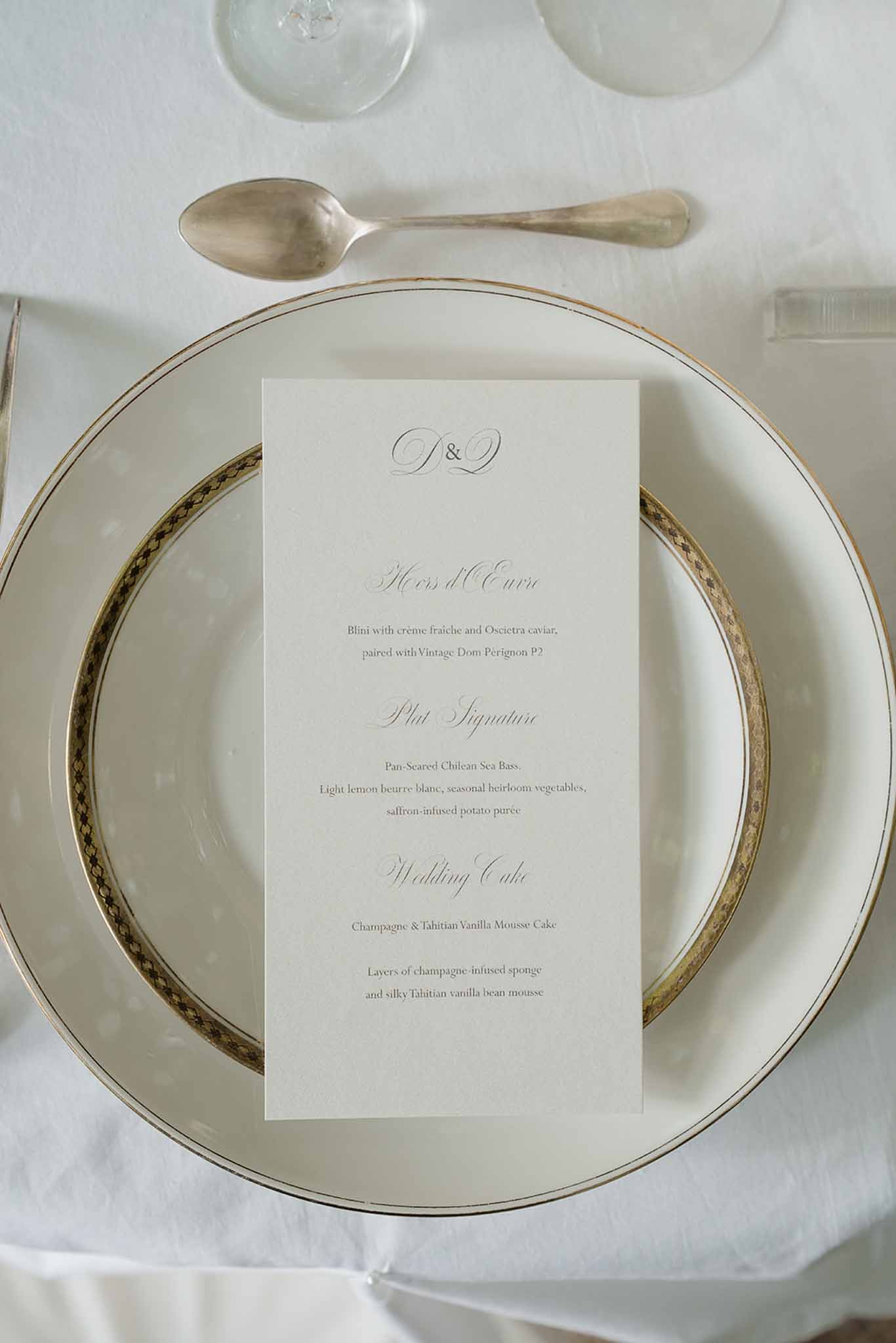 Ivory and gold-trimmed place setting with calligraphy menu card listing caviar and sea bass courses