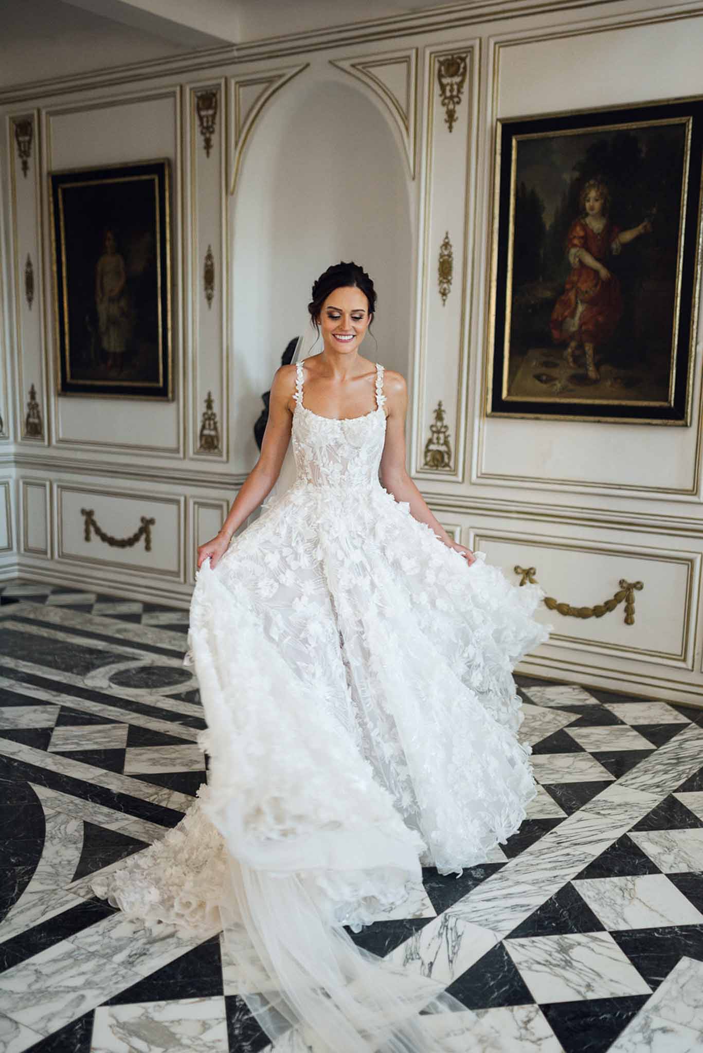 Bride fanning ivory 3D floral ballgown skirt in gilded boiserie room with marble floor and oil portraits