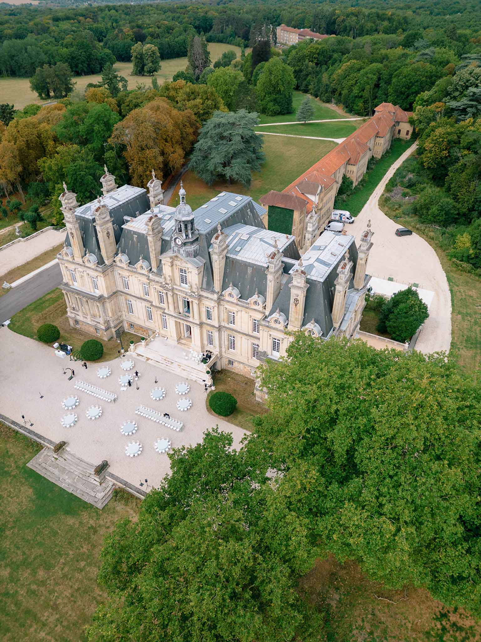 Aerial drone shot of Second Empire chateau with cocktail hour tables set up in gravel forecourt
