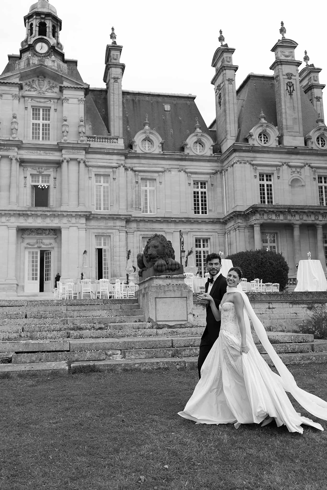 Black and white portrait of bride and groom on chateau stone staircase with lion statues