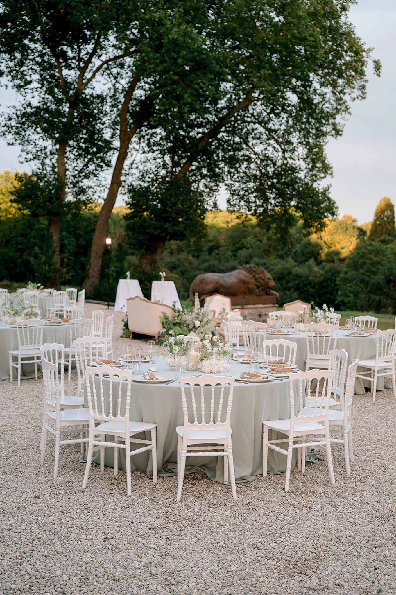 Dusk reception with sage linen round tables terracotta chargers white florals blush lounge area and bronze lion sculpture