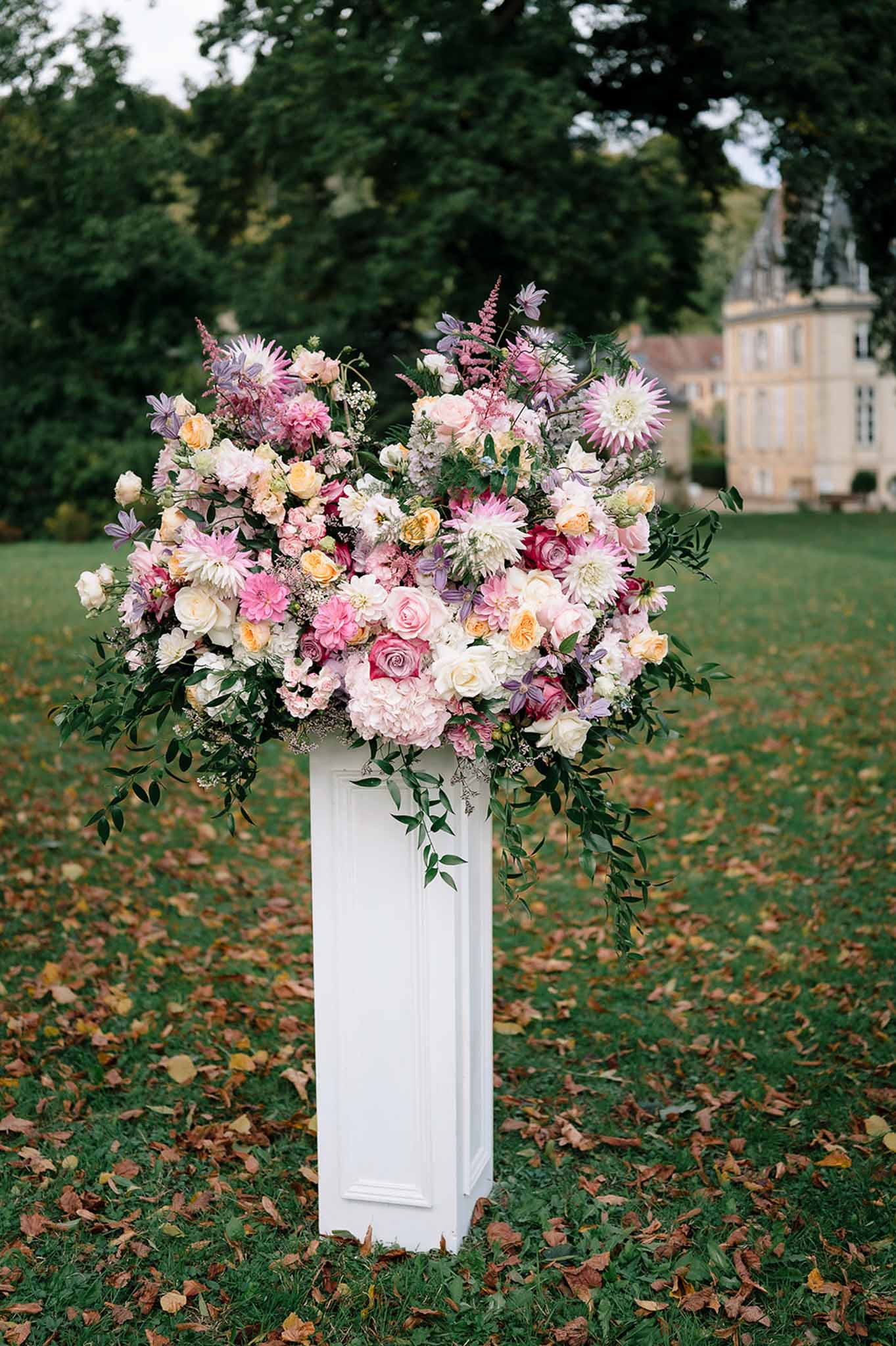 Oversized pedestal arrangement with pink hydrangeas, peach roses, and lavender clematis on lawn