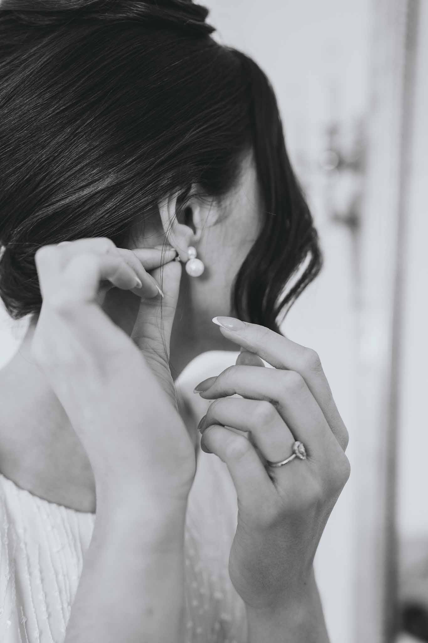 Close-up of bride putting on earrings during preparations