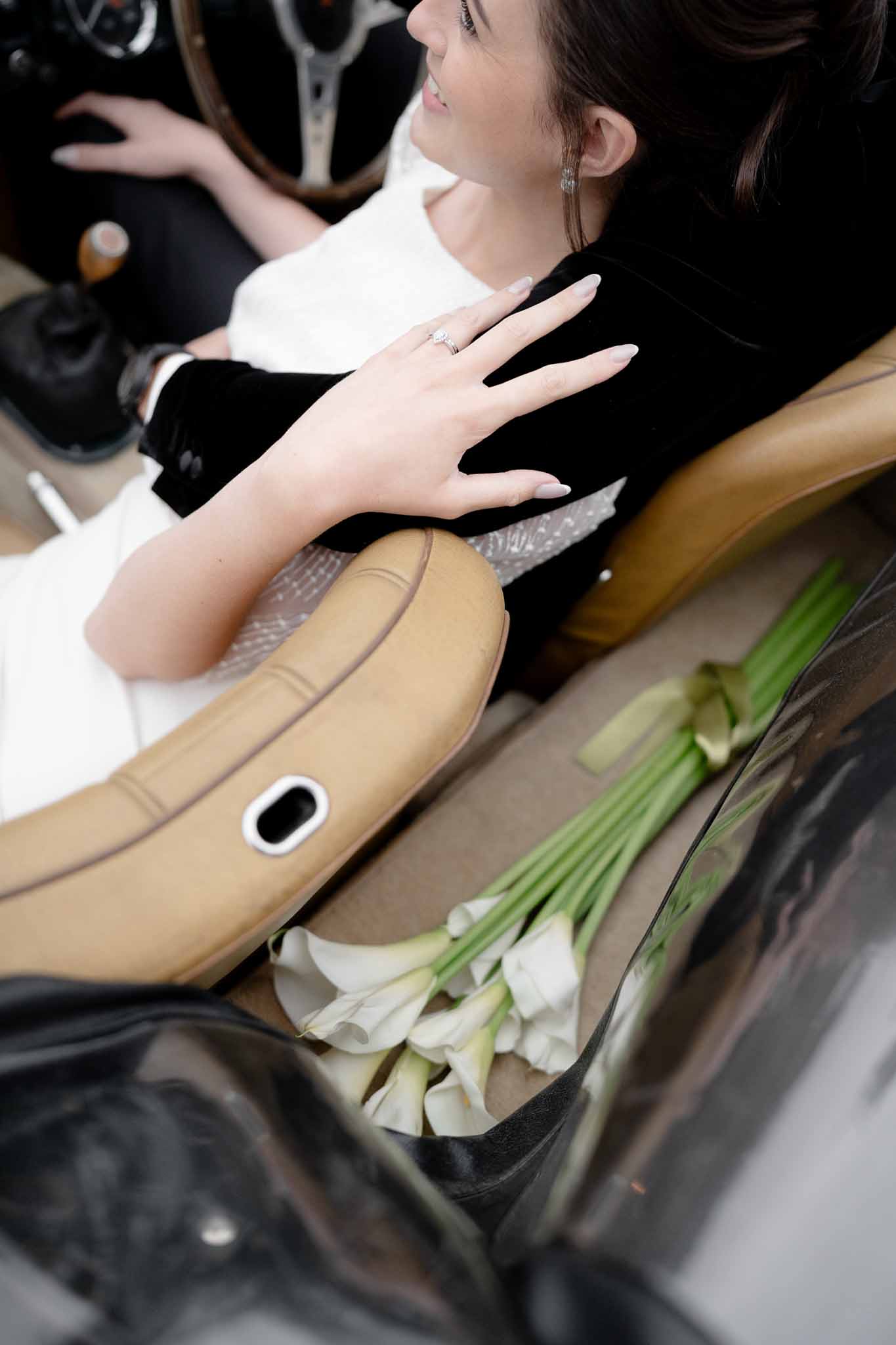 Bridal bouquet in focus with vintage car and couple blurred behind