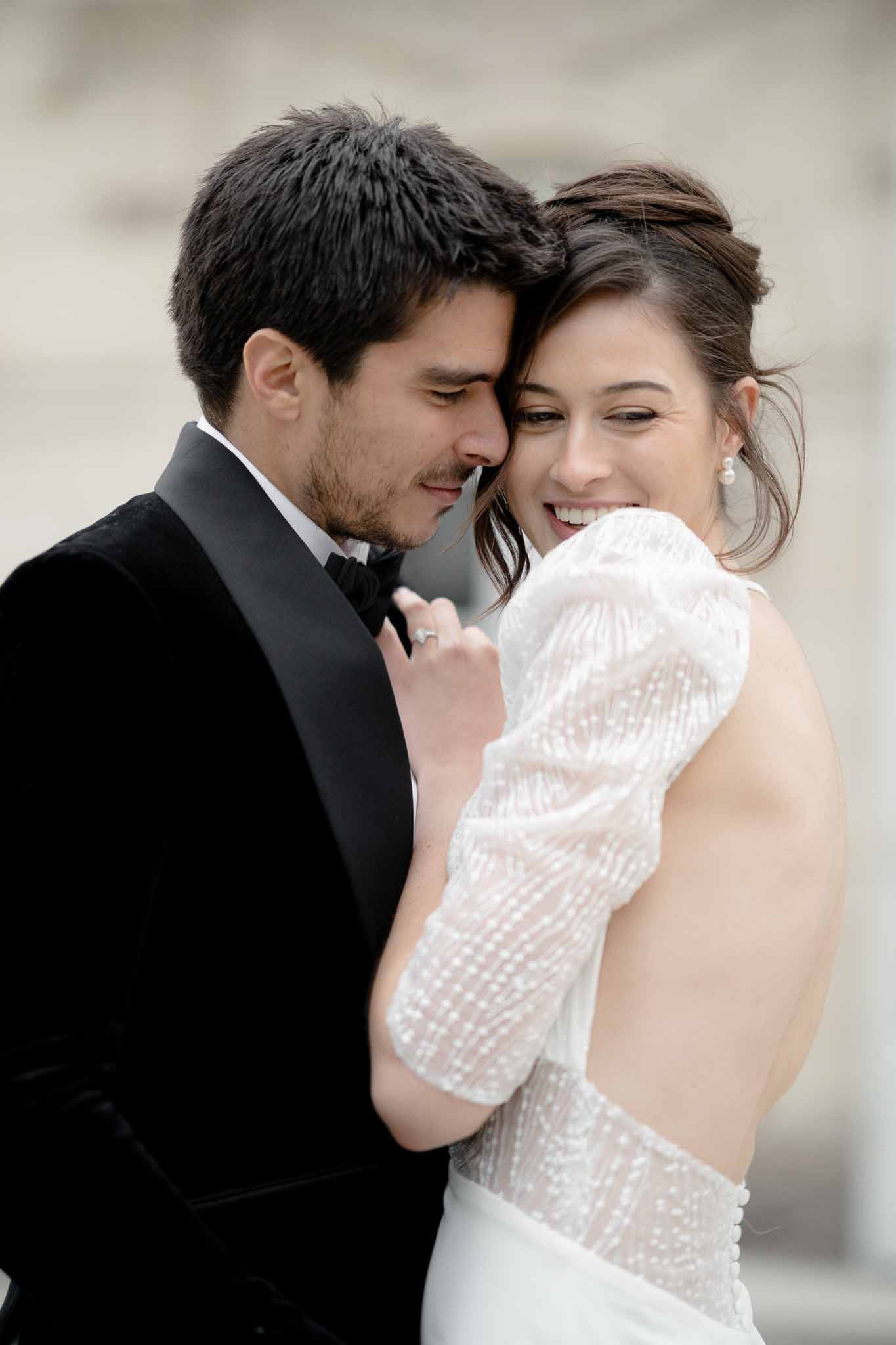 View of bride's open-back sparkly dress as groom embraces her