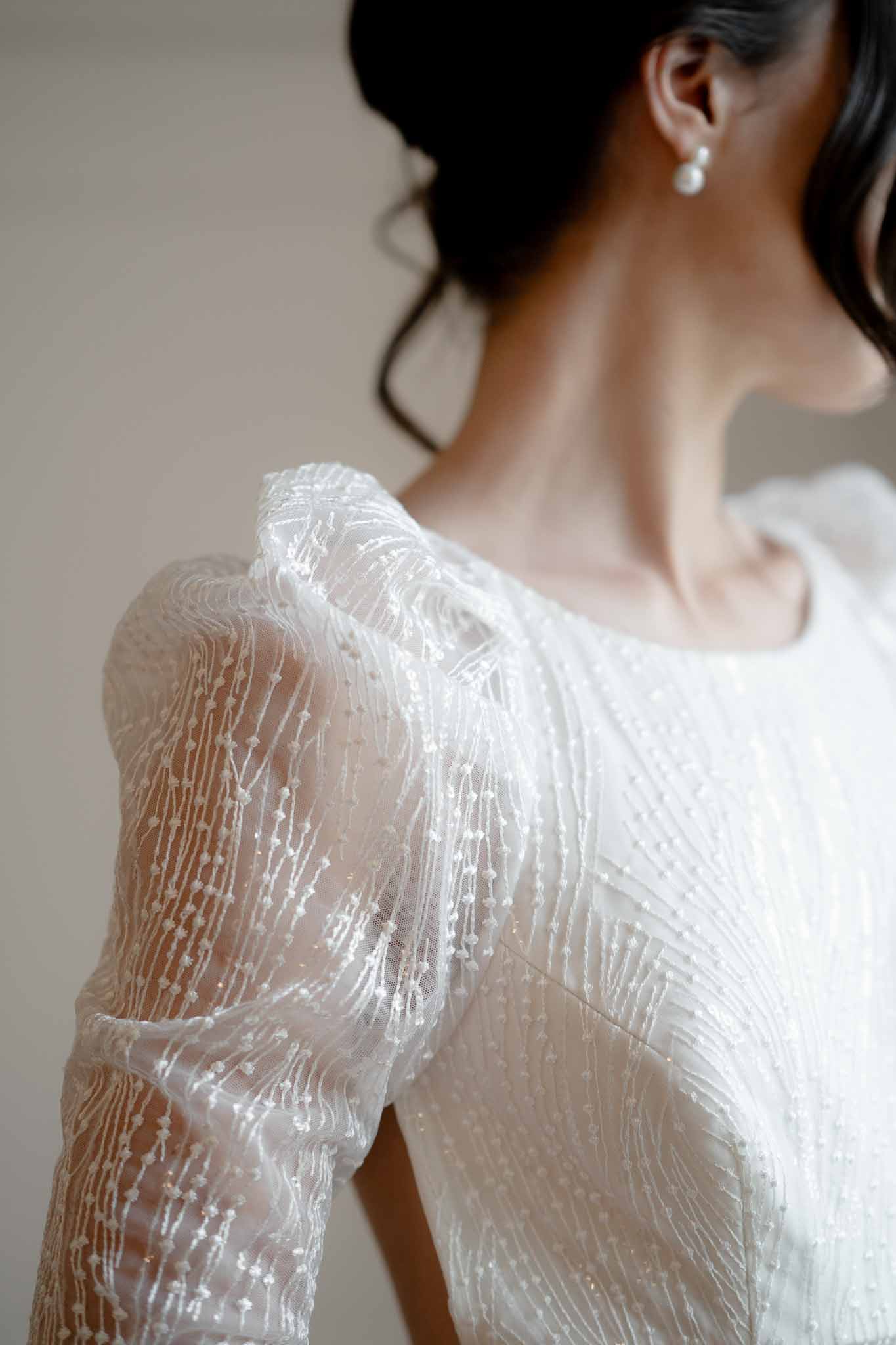 Detail shot of bride's sparkly dress with puff sleeves