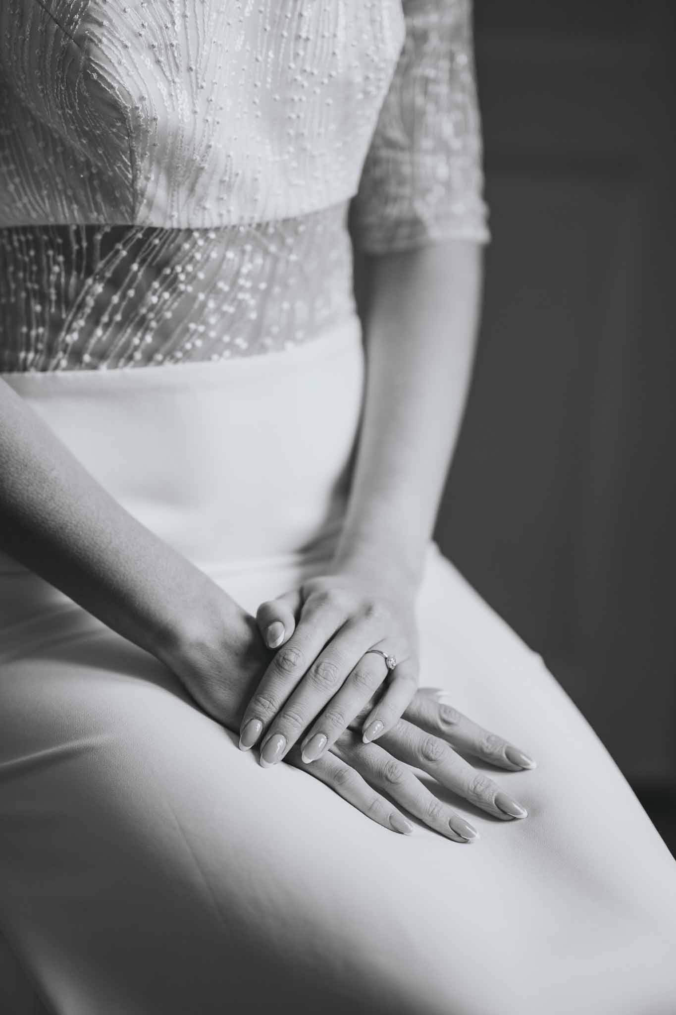Bride seated showing sparkly dress detail with hands in her lap