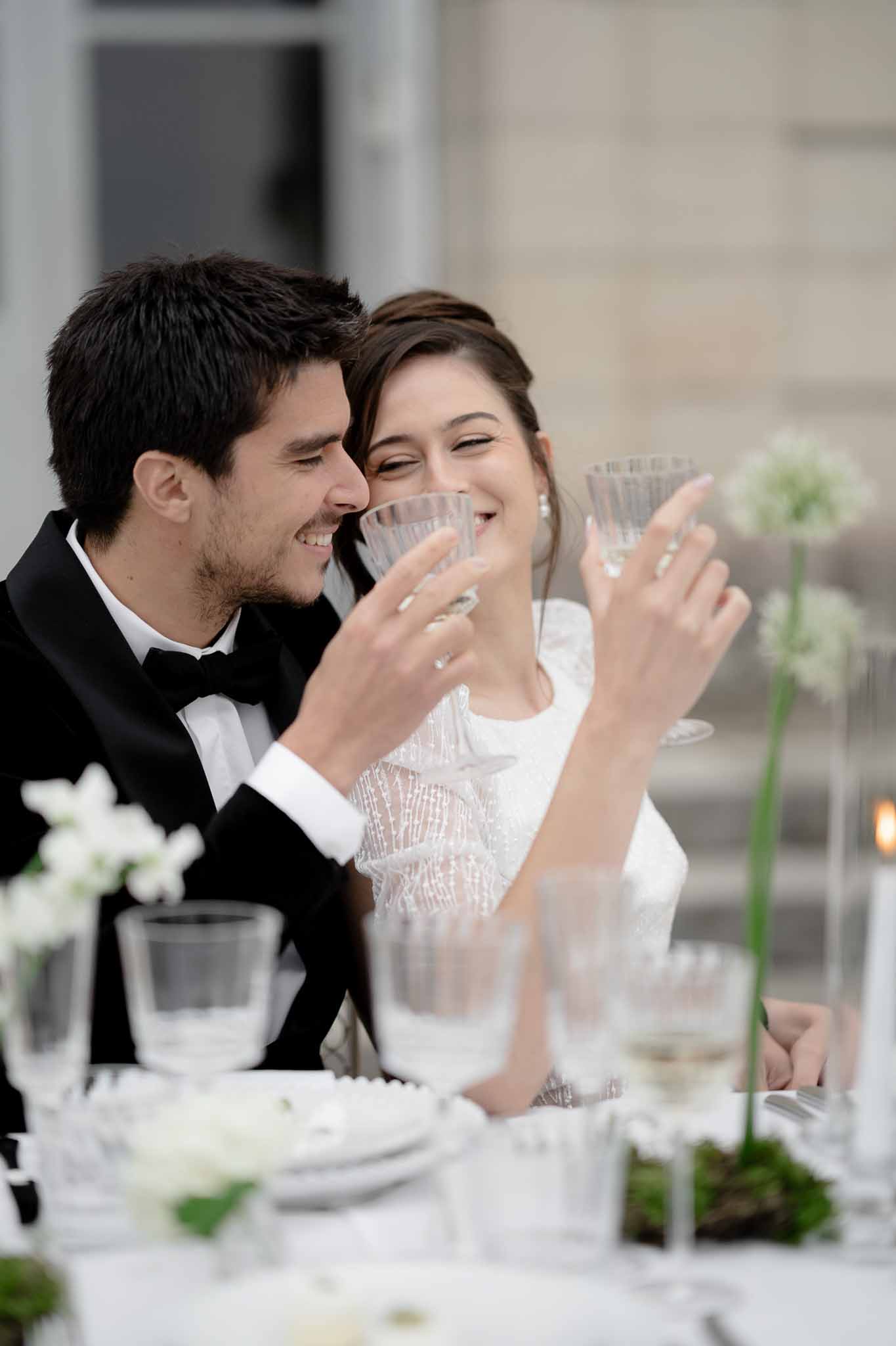 Couple raising champagne glasses in a toast at the reception table
