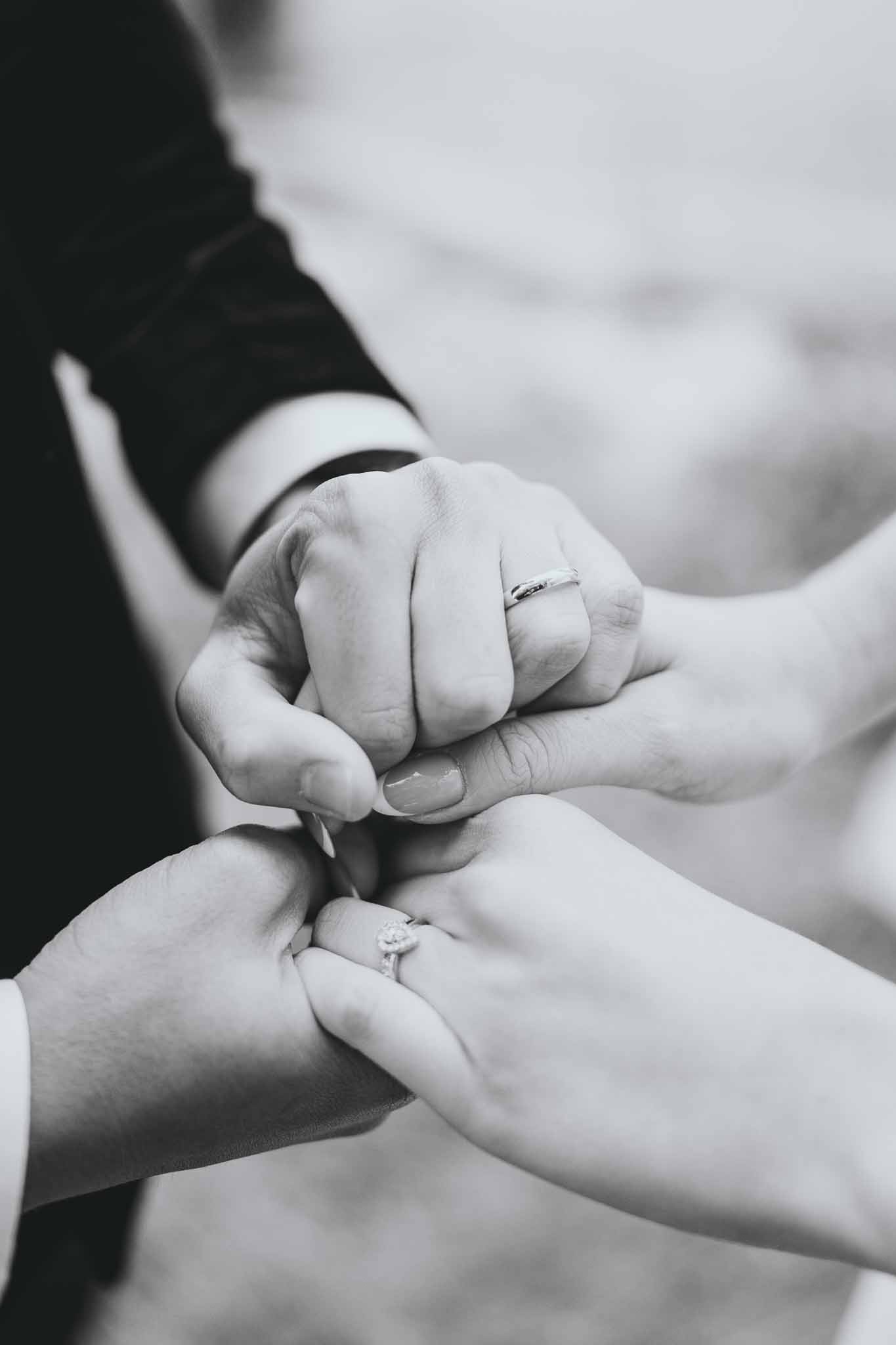 Close-up of couple's intertwined hands showing wedding rings