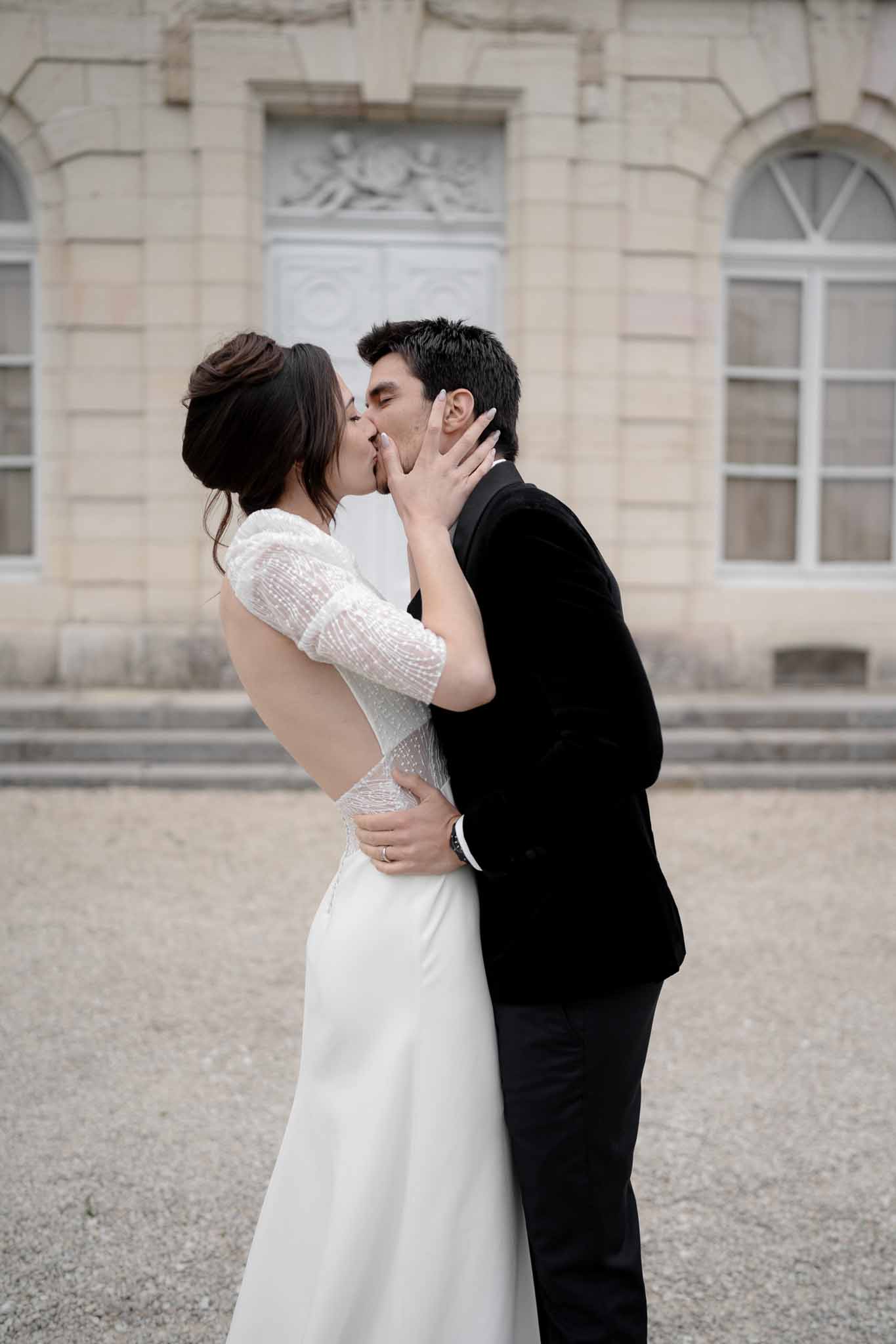 Bride holds groom's face tenderly as they share a kiss