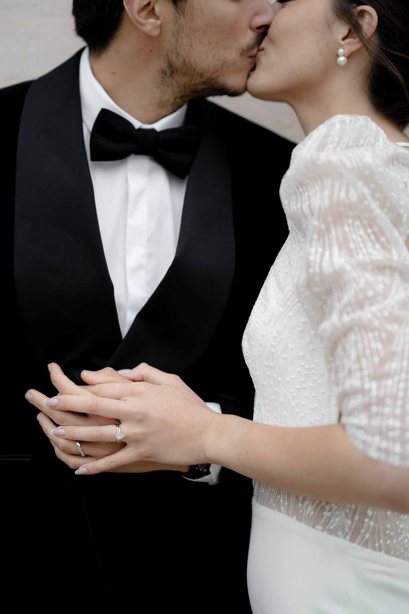 Couple sharing a kiss with their ringed hands in focus