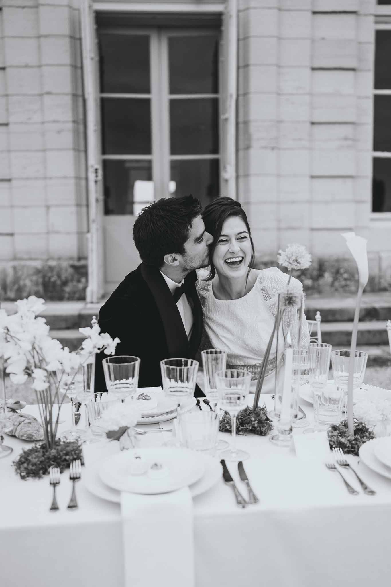 Couple sharing a kiss while seated at the reception table