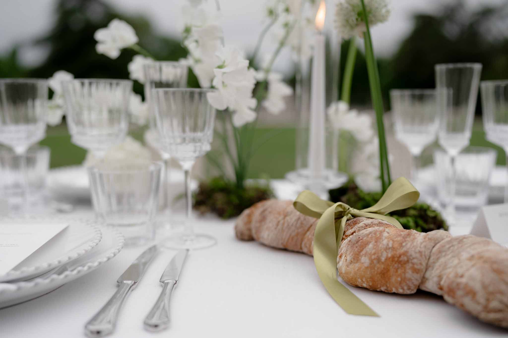 Plated food course alongside floral centerpiece and crystal glasses