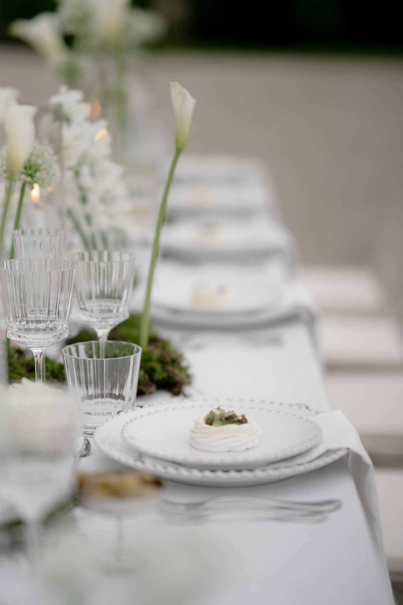 Plated food course alongside floral centerpiece on reception table