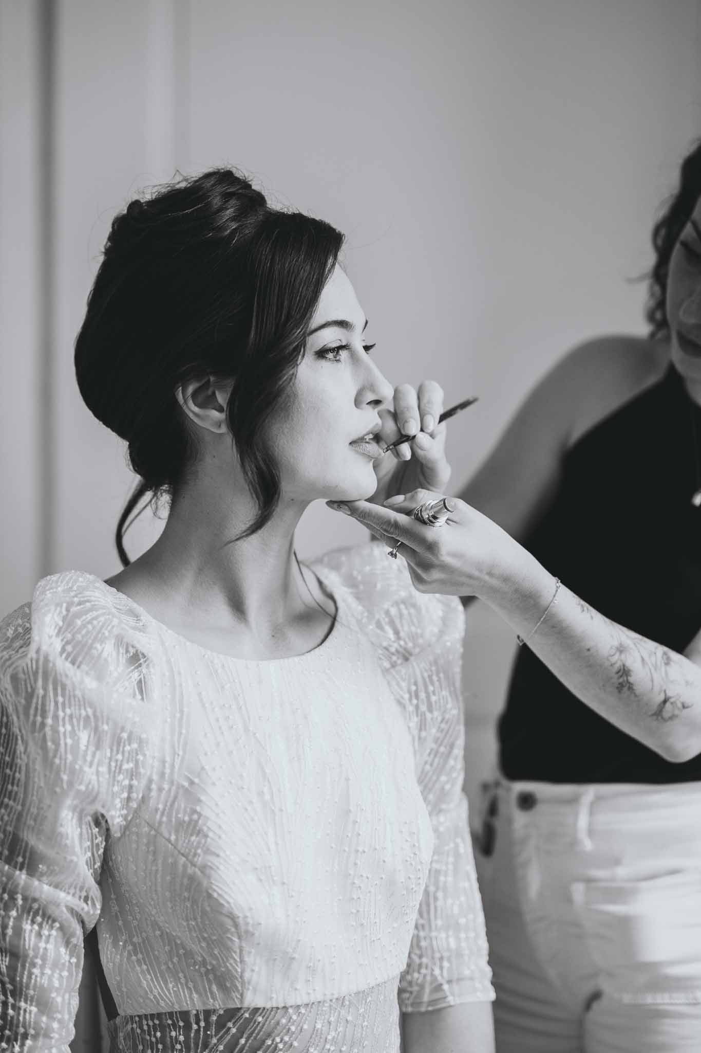Bride seated in chair during makeup preparation at Chateau d'Arcelot
