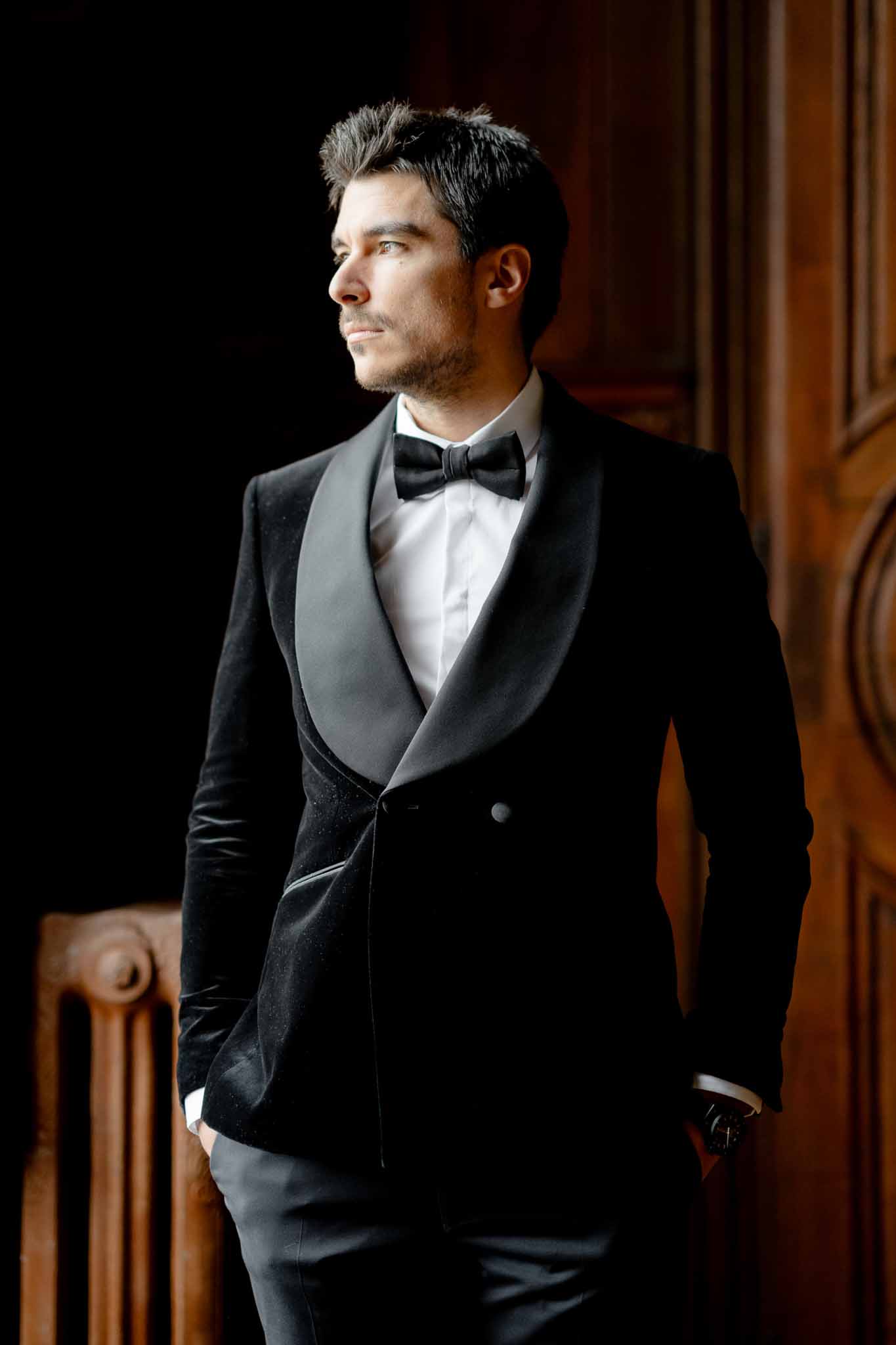 Groom preparing in black velvet suit at Chateau d'Arcelot