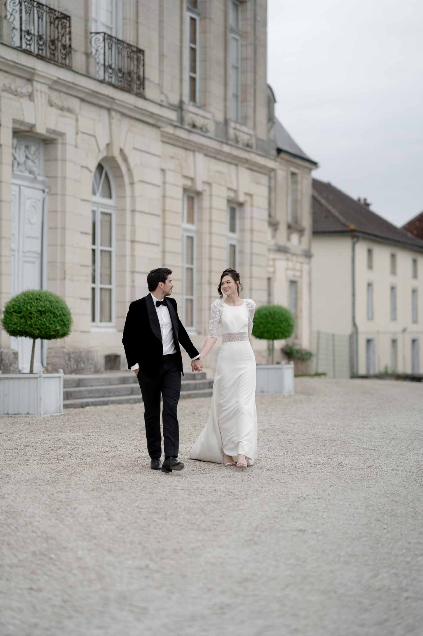 Bride and groom walking through the grand doorway of Chateau d'Arcelot