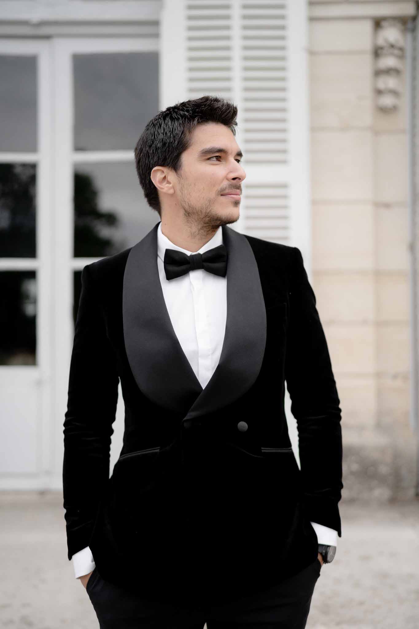 Close-up detail of groom's black velvet suit jacket and bow tie